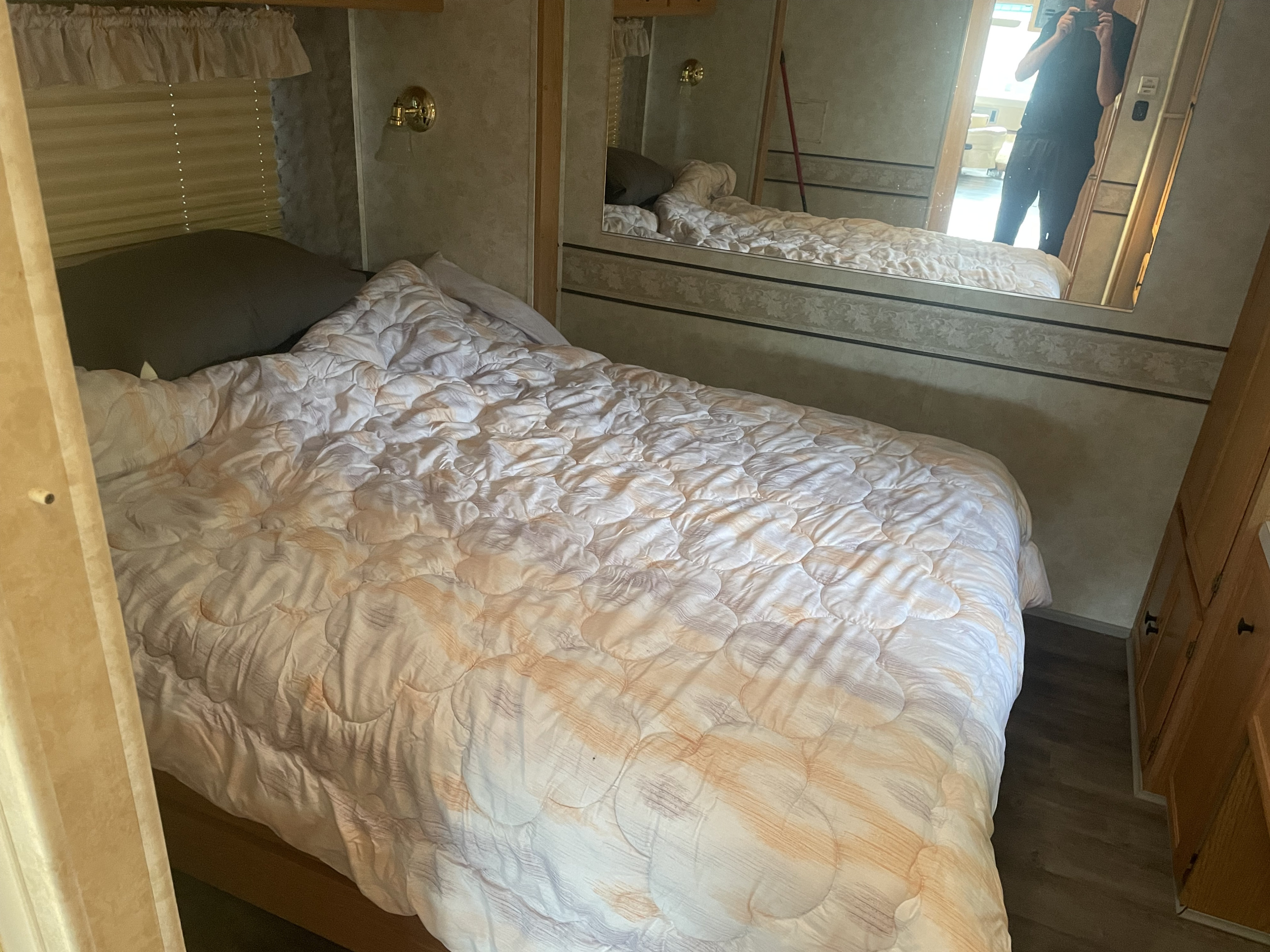 Cozy rv rental bedroom featuring a quilted comforter on the bed, a large mirror, and wood cabinetry.. Georgie Boy Pursuit 2001