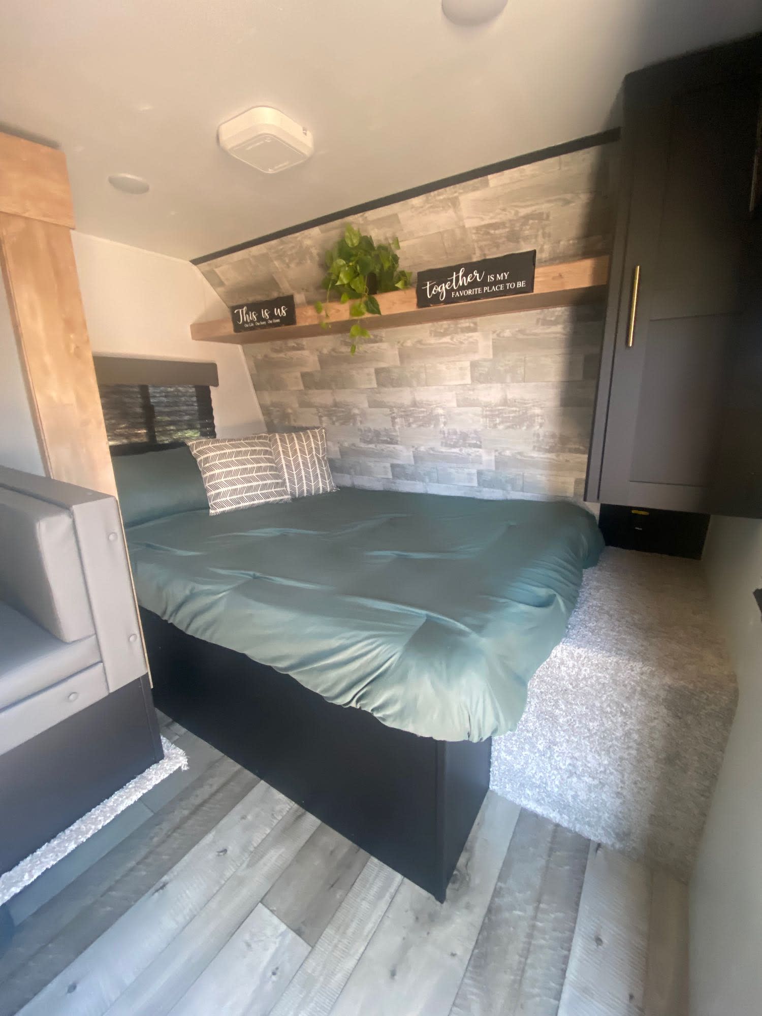 This RV rental features a compact, cozy bedroom with a bed, decorative wall, overhead shelving, and built-in storage.. Keystone RV Springdale 2022