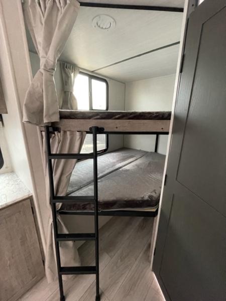 Comfortable bunk beds in an RV rental interior. Ideal for families, featuring a ladder and cozy sleeping areas.. Forest River Surveyor Legend 260BHLE 2023
