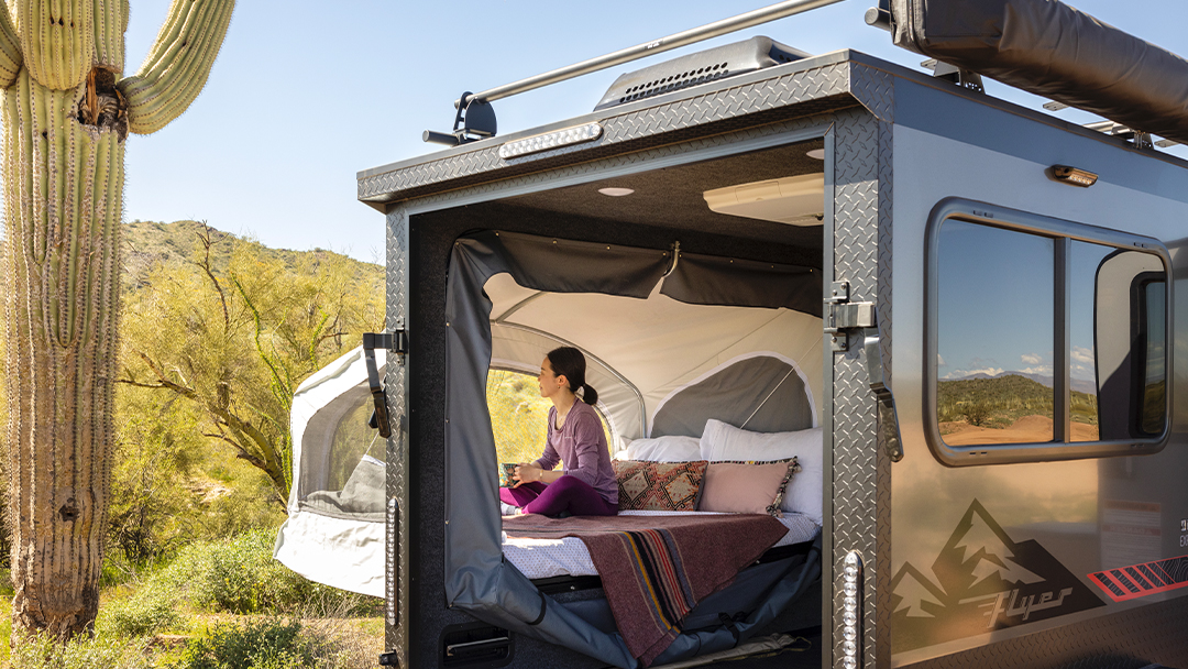 Enjoy desert views from a compact rv rental! A woman relaxes inside a cozy pop-up camper amidst saguaro cacti.. Intech Explore 2023