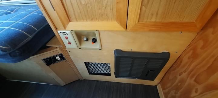 RV rental interior: furnace/heating controls, vents, and a blue bed. Comfort features for your journey.. Winnebago Lesharo 1985