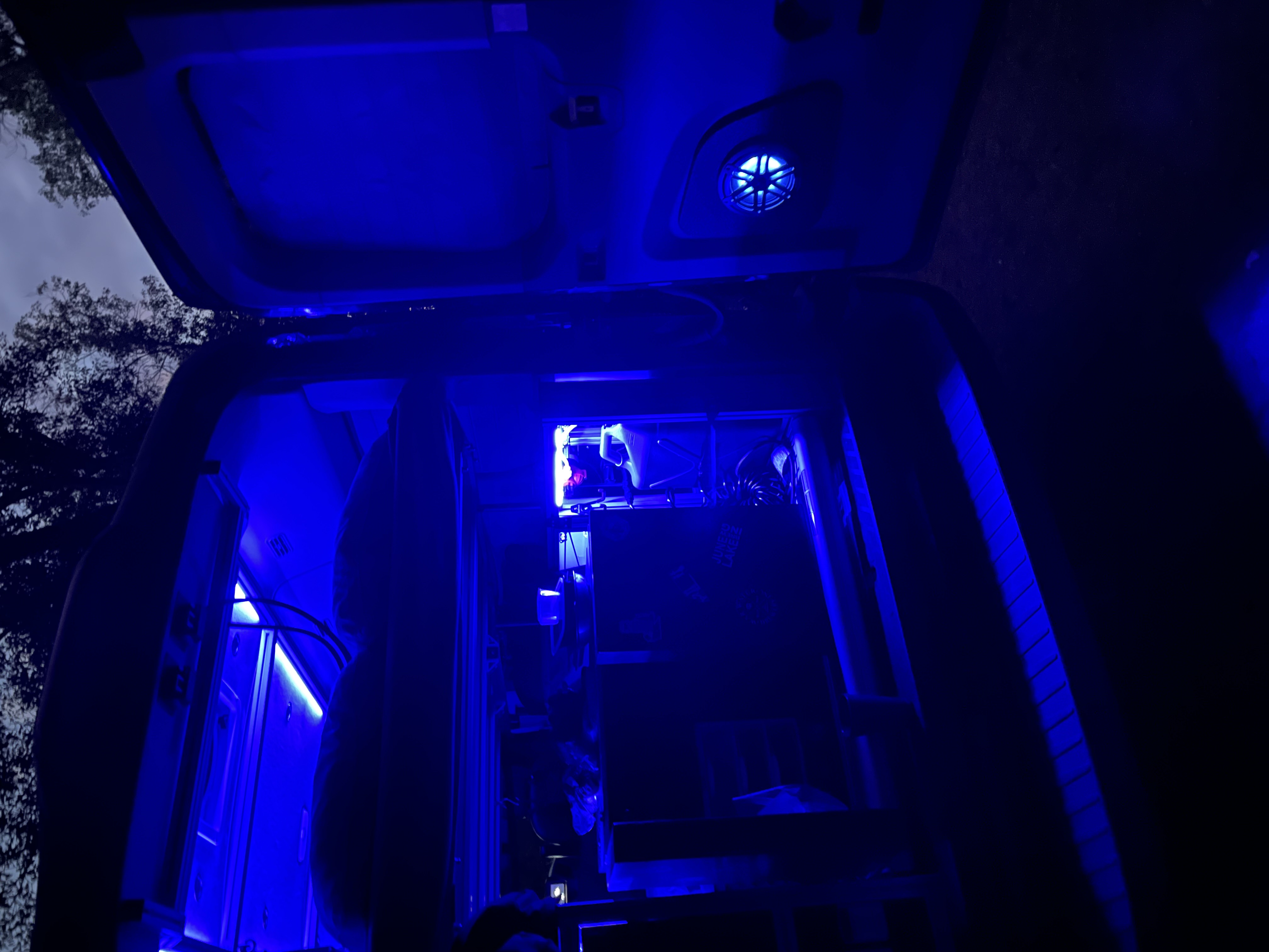 Blue-lit RV rental interior at night, showcasing a custom computer setup. Perfect for unique tech travel experiences.. Ford Transit 2018