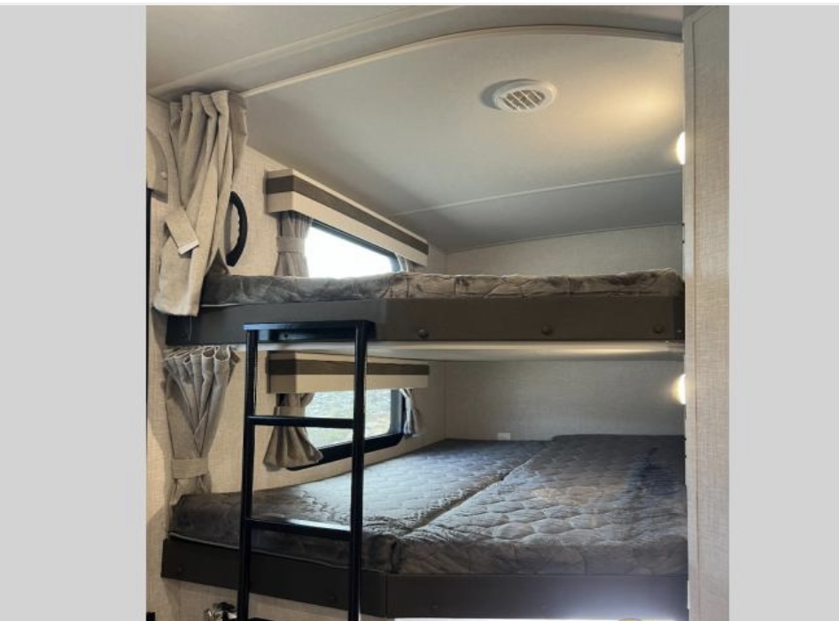 Spacious RV rental bunk beds with comfortable mattresses, ideal for family trips. Features ladder & windows.. Forest River Rockwood Ultra Lite 2023