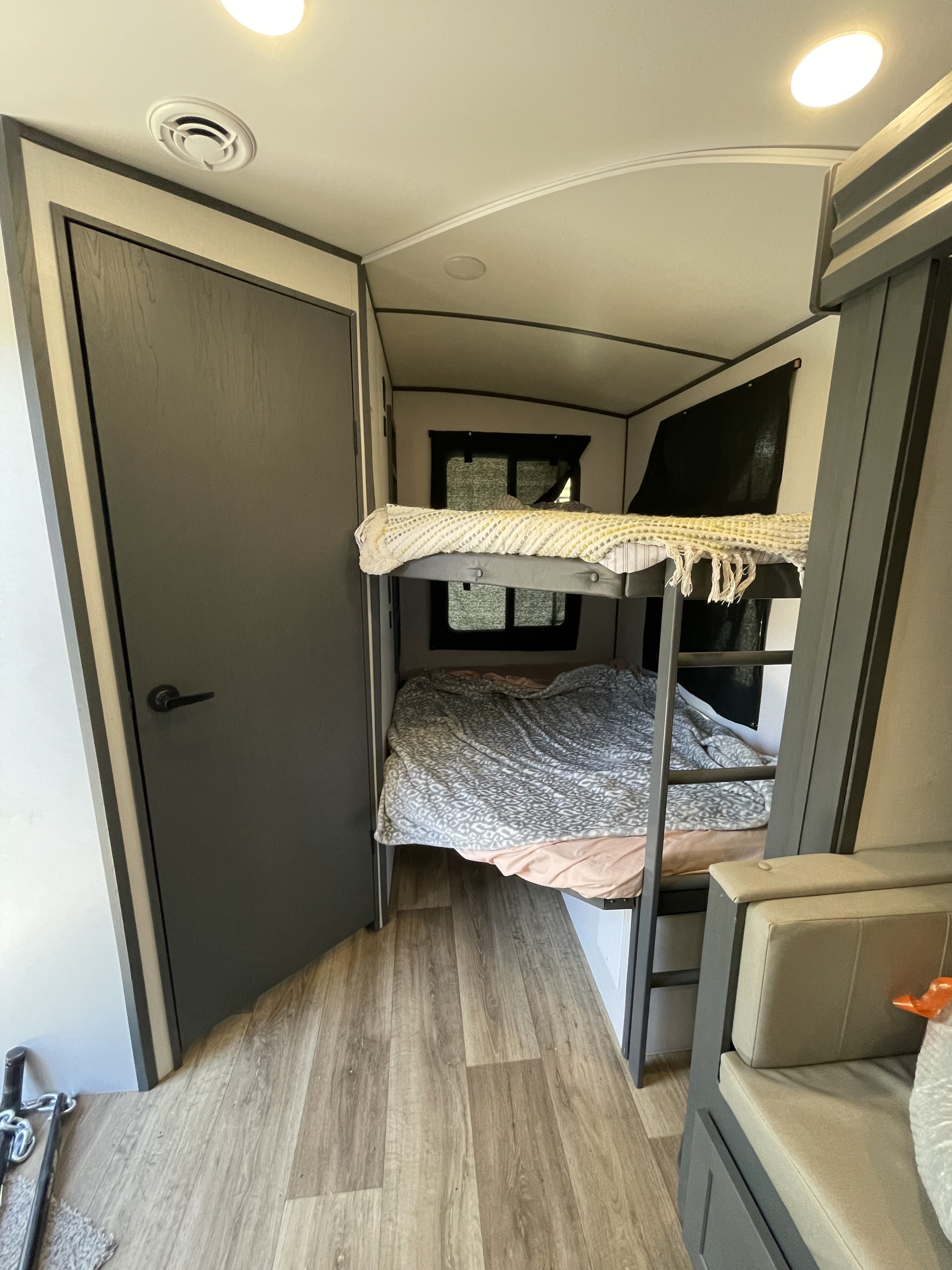 RV rental interior showing comfortable bunk beds, a door, and lounge seating, perfect for families.. Keystone RV Bullet Ultra Lite 2023