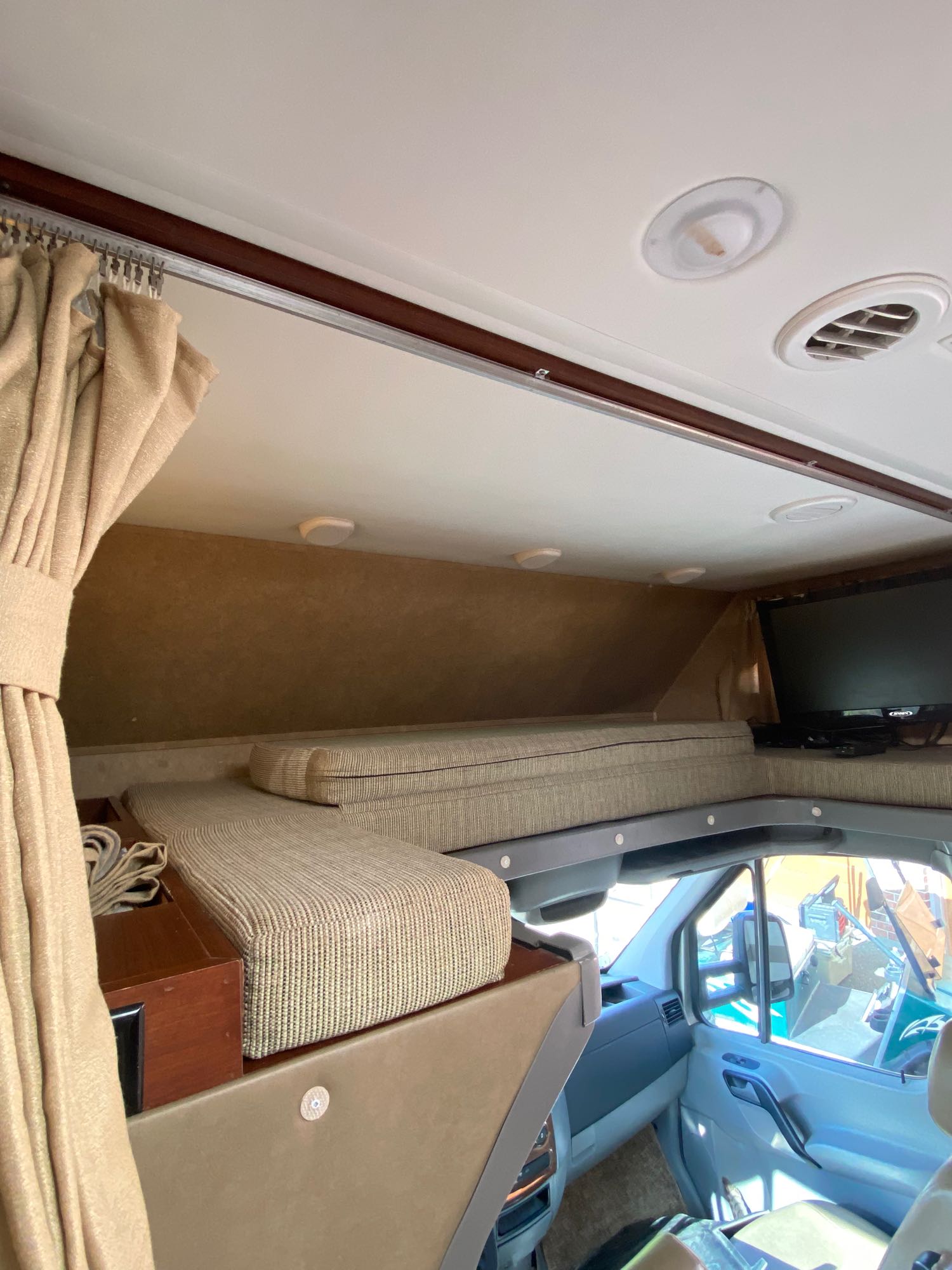 RV rental interior: A cozy overhead bunk bed with cushions, built-in TV, and view into the front cabin.. Solera Solera Motorhome 2014