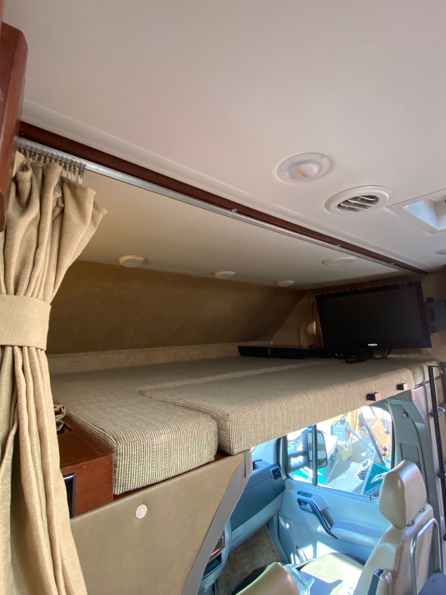 Inside this RV rental: a comfy over-cab bunk bed with a TV.. Solera Solera Motorhome 2014