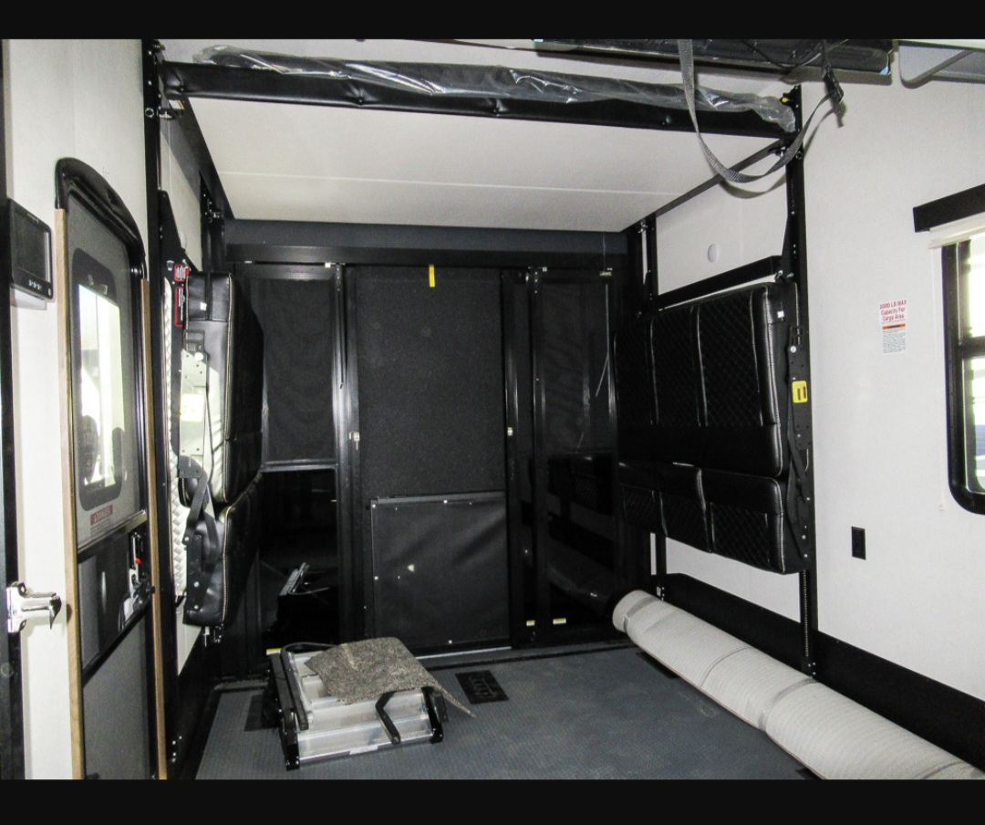 RV rental toy hauler interior: versatile cargo space with fold-away bunks and open floor, perfect for gear.. Keystone RV Fuzion Toy Hauler 2021