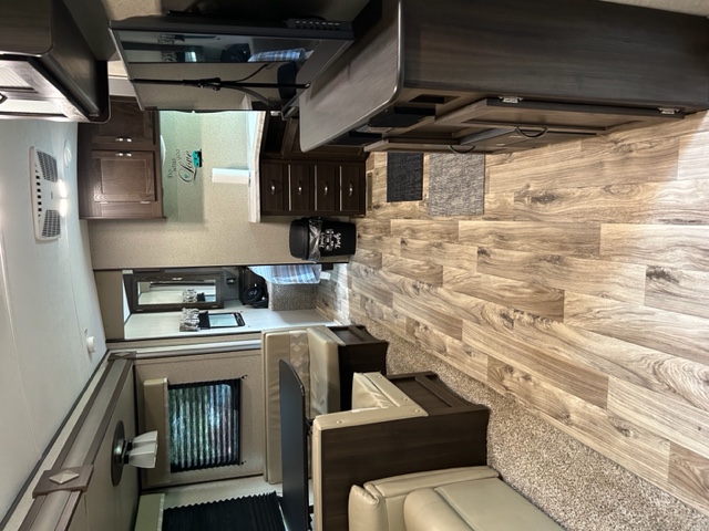RV rental interior: Spacious living area with cream sofas, dark kitchen cabinets, wood floors, and a TV.. Keystone RV Springdale 2018
