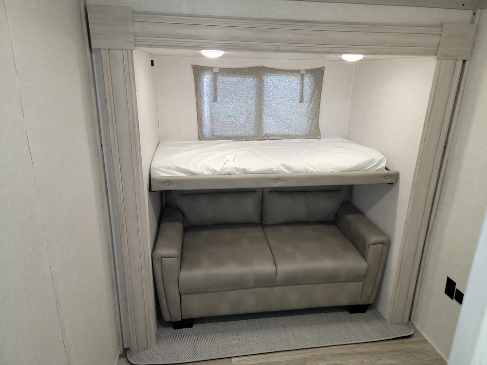 RV rental interior: a compact bunk bed system with a sofa below, optimizing space for both sleeping and a lounge area.. East to West Tandara 2022