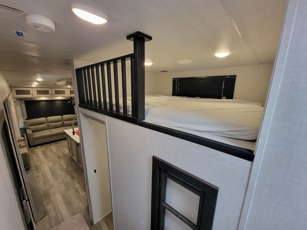 Modern rv rental interior featuring a spacious loft bedroom above the main living area and kitchen.. East to West Tandara 2022