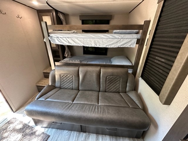 RV rental interior showcasing comfy bunk beds, a pull-out sofa, and steps. Ideal family camping space.. Grand Design 265BH 2022