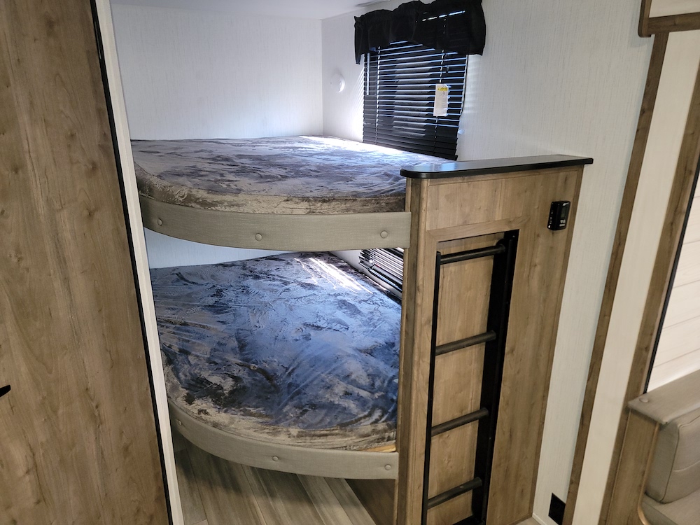 RV rental: Cozy bunk bed area featuring two beds with patterned mattresses & an access ladder.. Heartland RVs Pioneer 2023