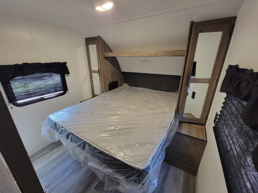 Step inside this RV rental bedroom: a new bed, built-in wardrobes, and windows with blinds offer comfort and convenience.. Heartland RVs Pioneer 2023