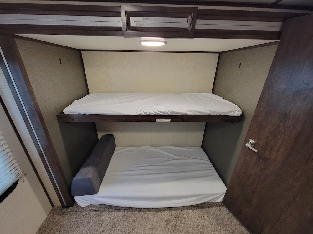 RV rental bunk beds: a clean, comfortable sleeping area with fresh white sheets and overhead light.. Cruiser RV Embrace Ultra Lite 2020
