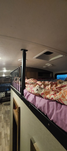 Inside an RV rental: a cozy loft bed with a protective railing, overlooking the living space below.. Keystone RV Montana 2017