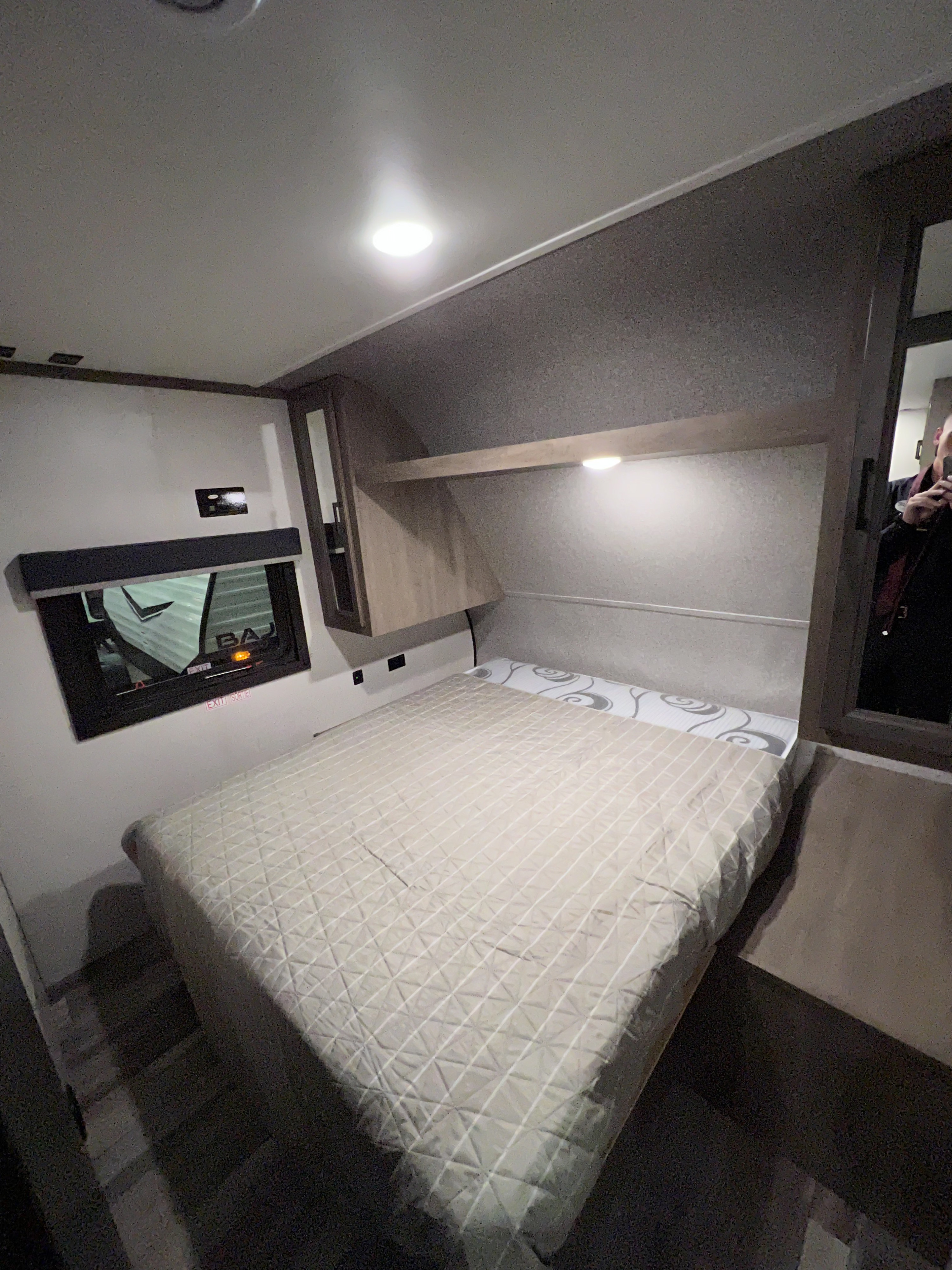 Cozy RV rental bedroom showing a quilted bed, overhead light, window, and mirrored closet. Ideal for travel.. Highland Ridge RV Open Range 2022