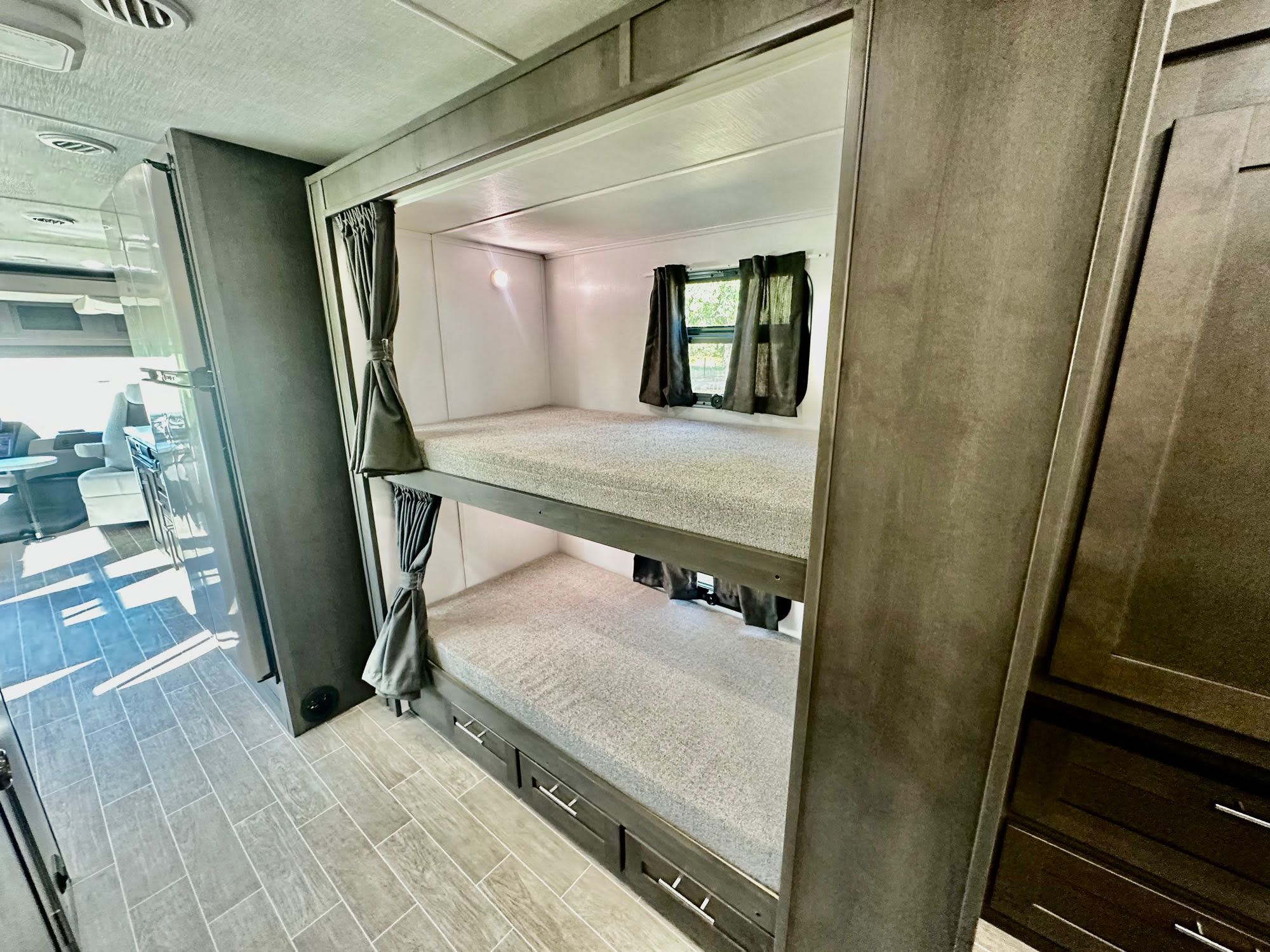 Spacious RV rental with practical bunk beds & storage, light wood-look floors, and a bright living area reflection.. Forest River Georgetown 5 Series 2023