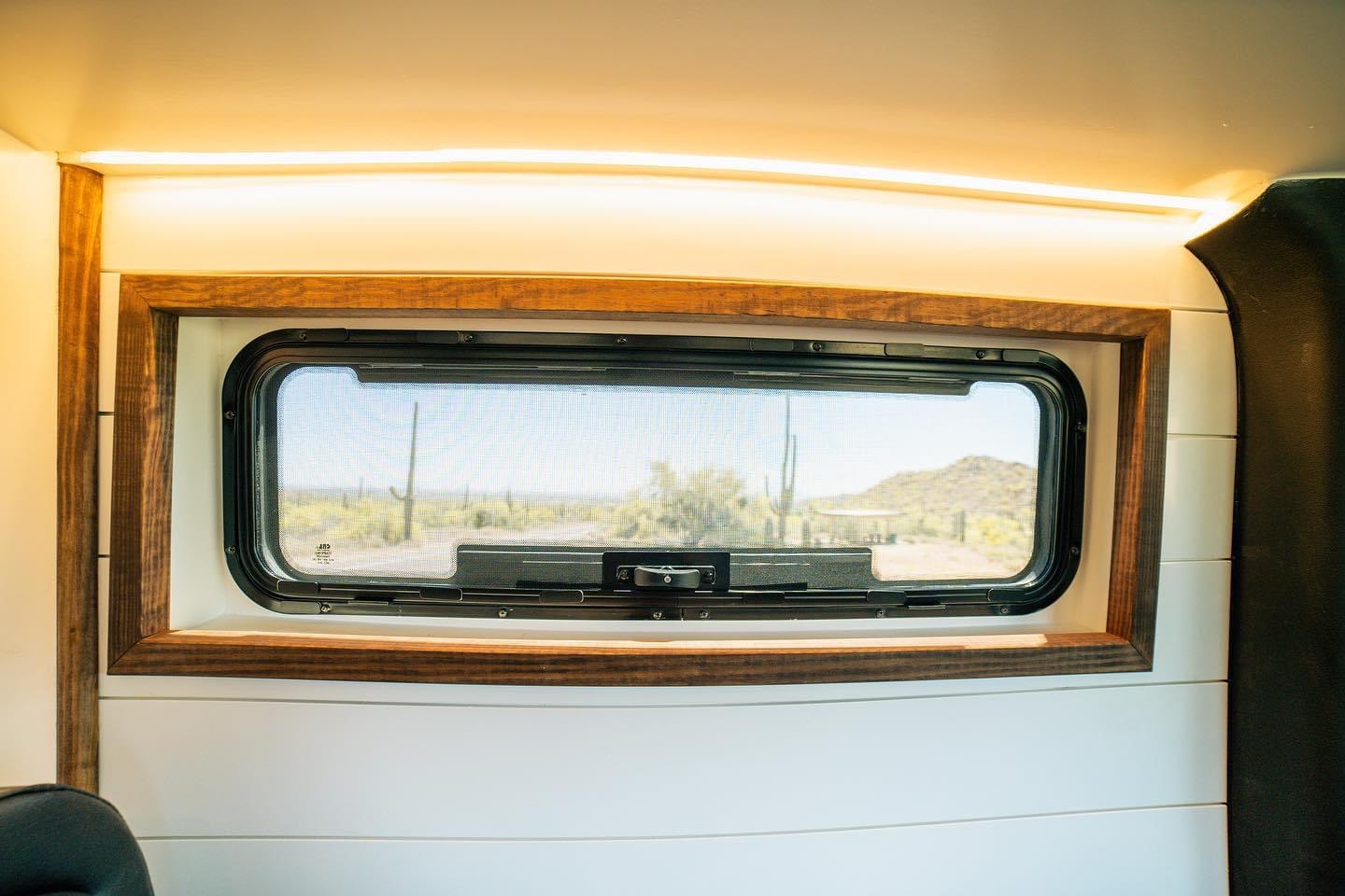 RV rental interior: A window framed in wood, white walls, and LED lighting, revealing a desert view with cacti.. Mercedes Benz Mercedes Sprinter 2500 2023