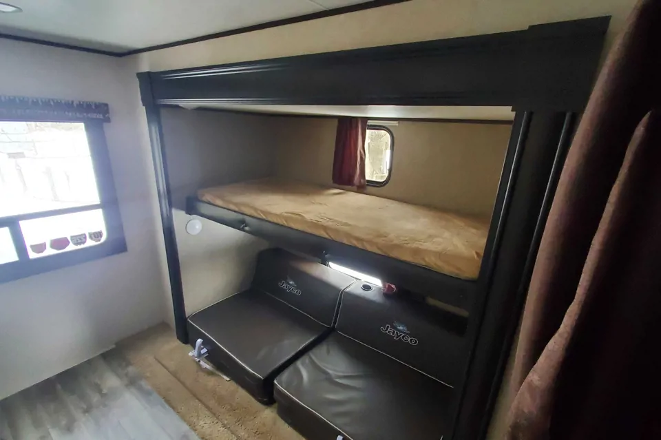 RV rental interior featuring cozy bunk beds and a convertible seating area, perfect for compact family travel.. Jayco Jay Flight SLX 2018