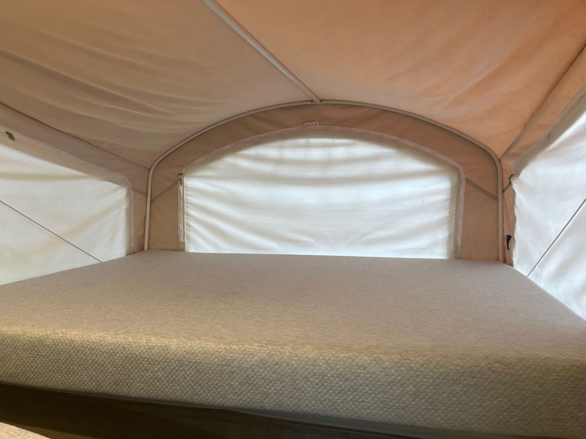 RV rental interior: a clean mattress fills this pop-up sleeping area, with canvas walls & an 'EXIT' sign.. Coachmen Other 2017