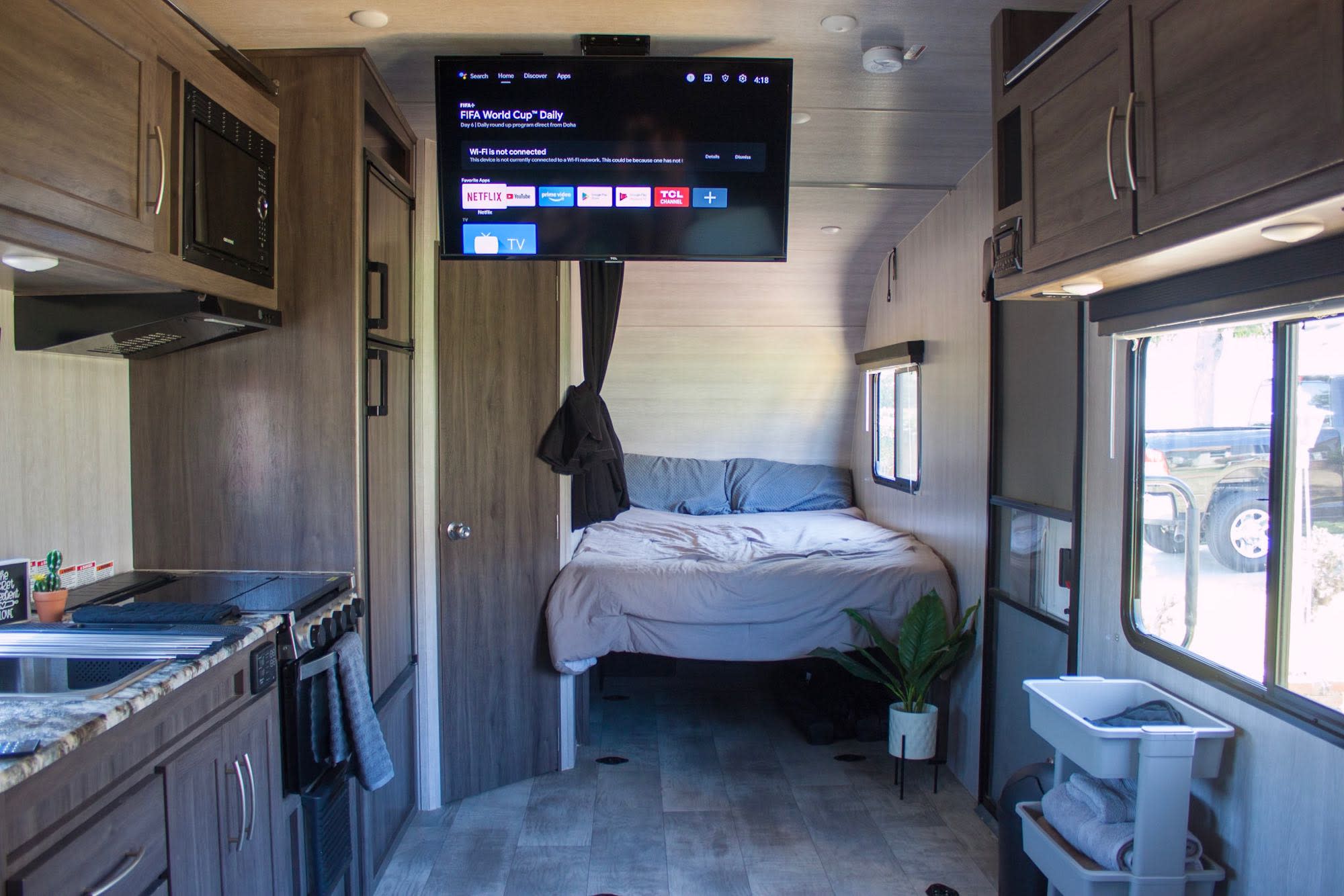 Cozy RV rental interior featuring a kitchen, bed, and a ceiling-mounted TV with streaming apps for on-the-go comfort.. Genesis Supreme Rv Genesis Supreme 2022