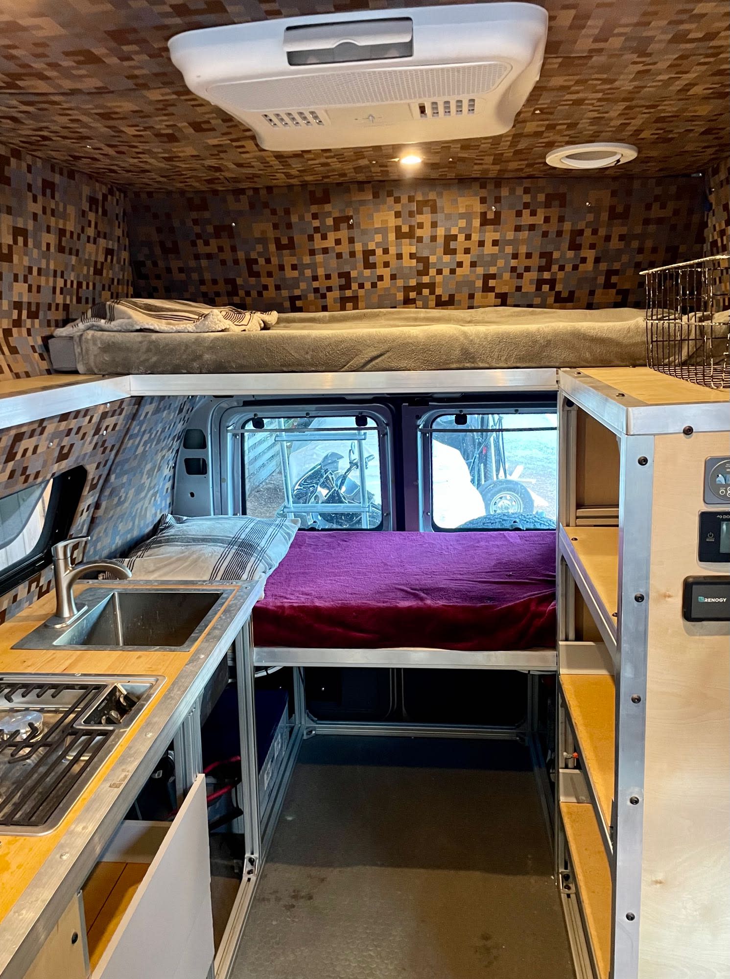View of a modern RV rental camper van interior. Features a kitchen with sink/stove, bunk beds, and patterned walls.. Ford Airstream B190 1993