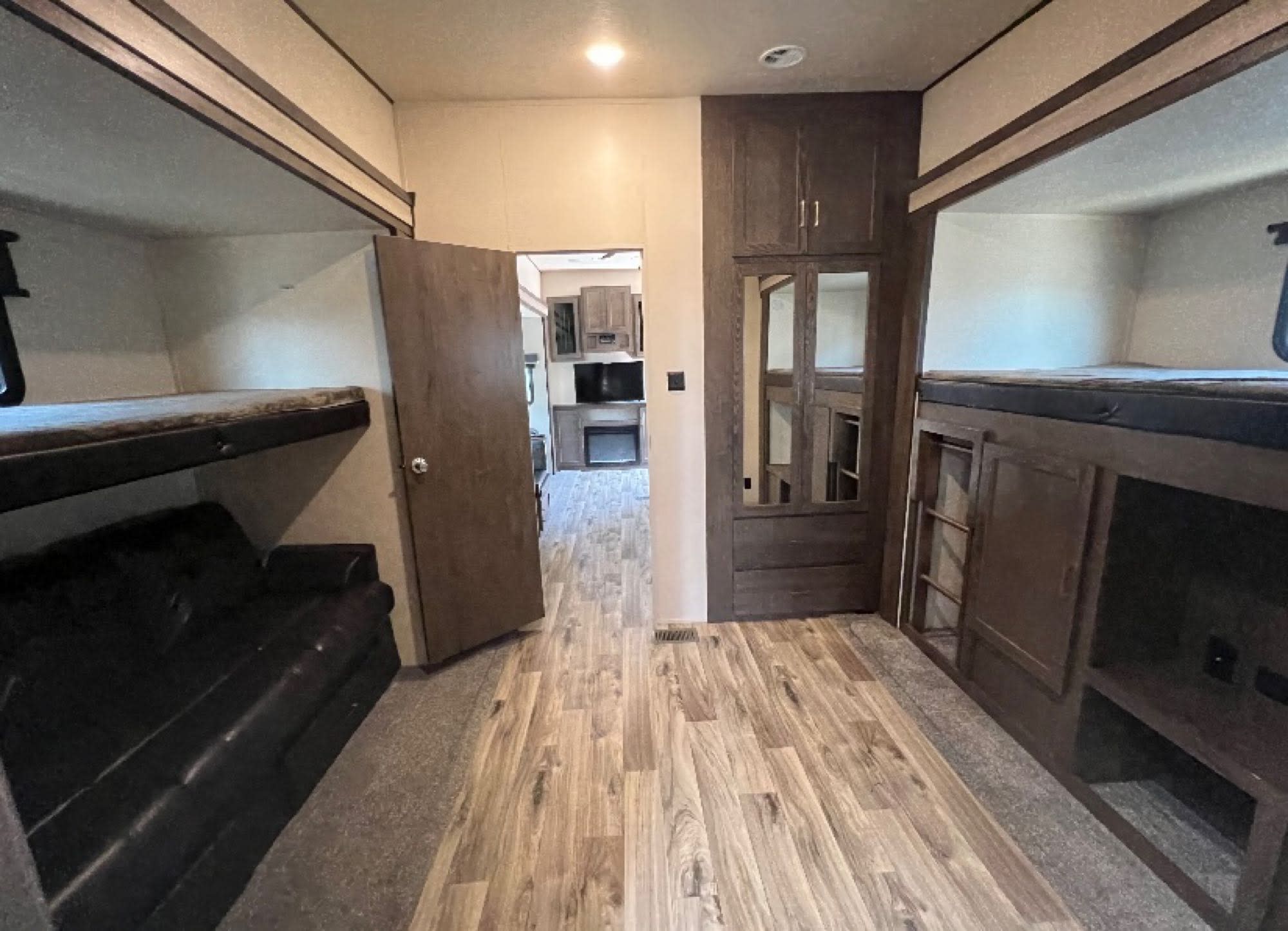 Spacious RV rental bunk room with multiple bunks, a sofa, and storage, offering comfort for larger groups.. Forest River Salem Hemisphere GLX 2019