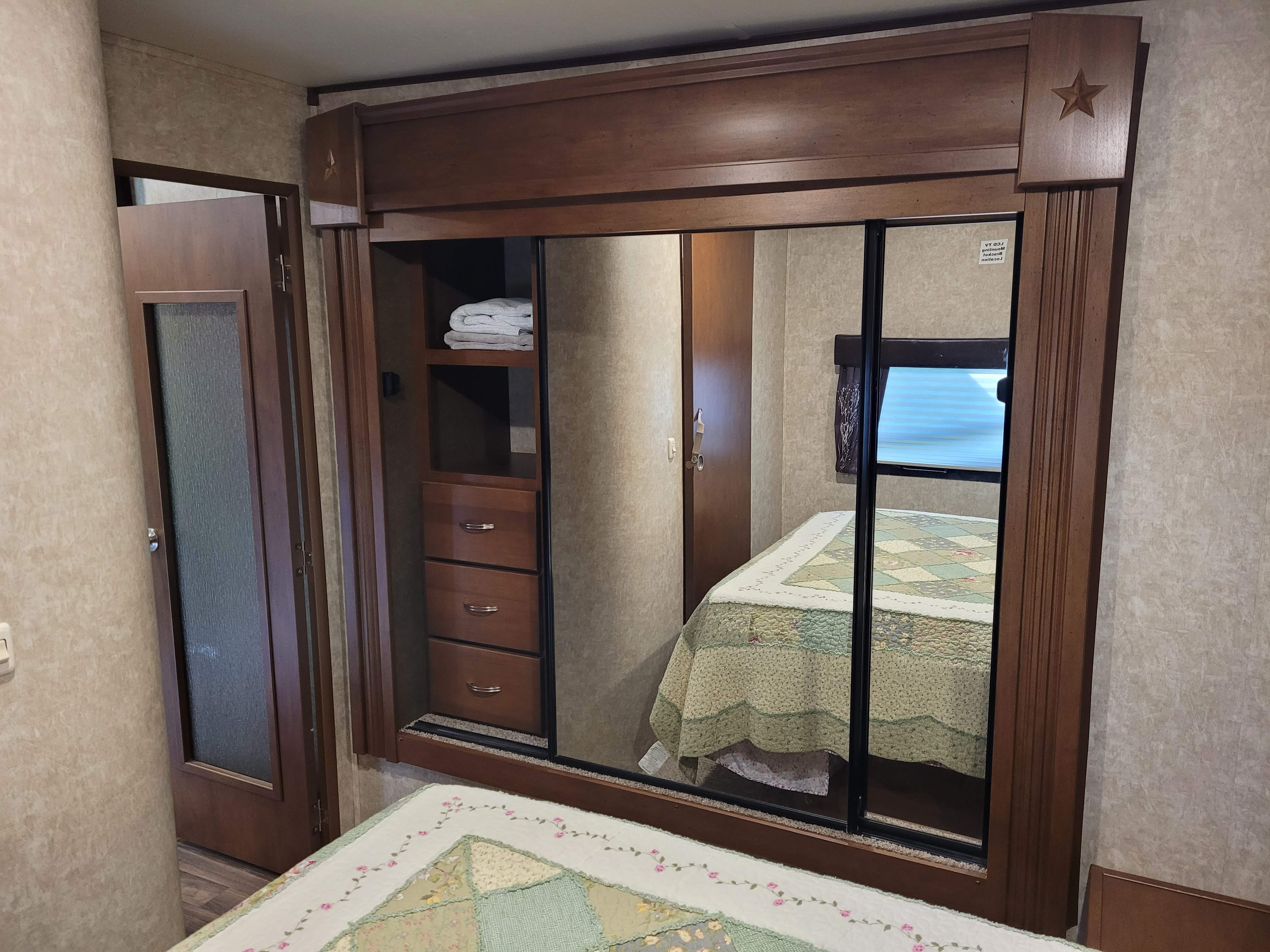 RV rental bedroom with a large mirrored wardrobe, built-in shelves & drawers, and a quilted bed. Cozy and functional.. Highland Ridge RV Roamer 2016
