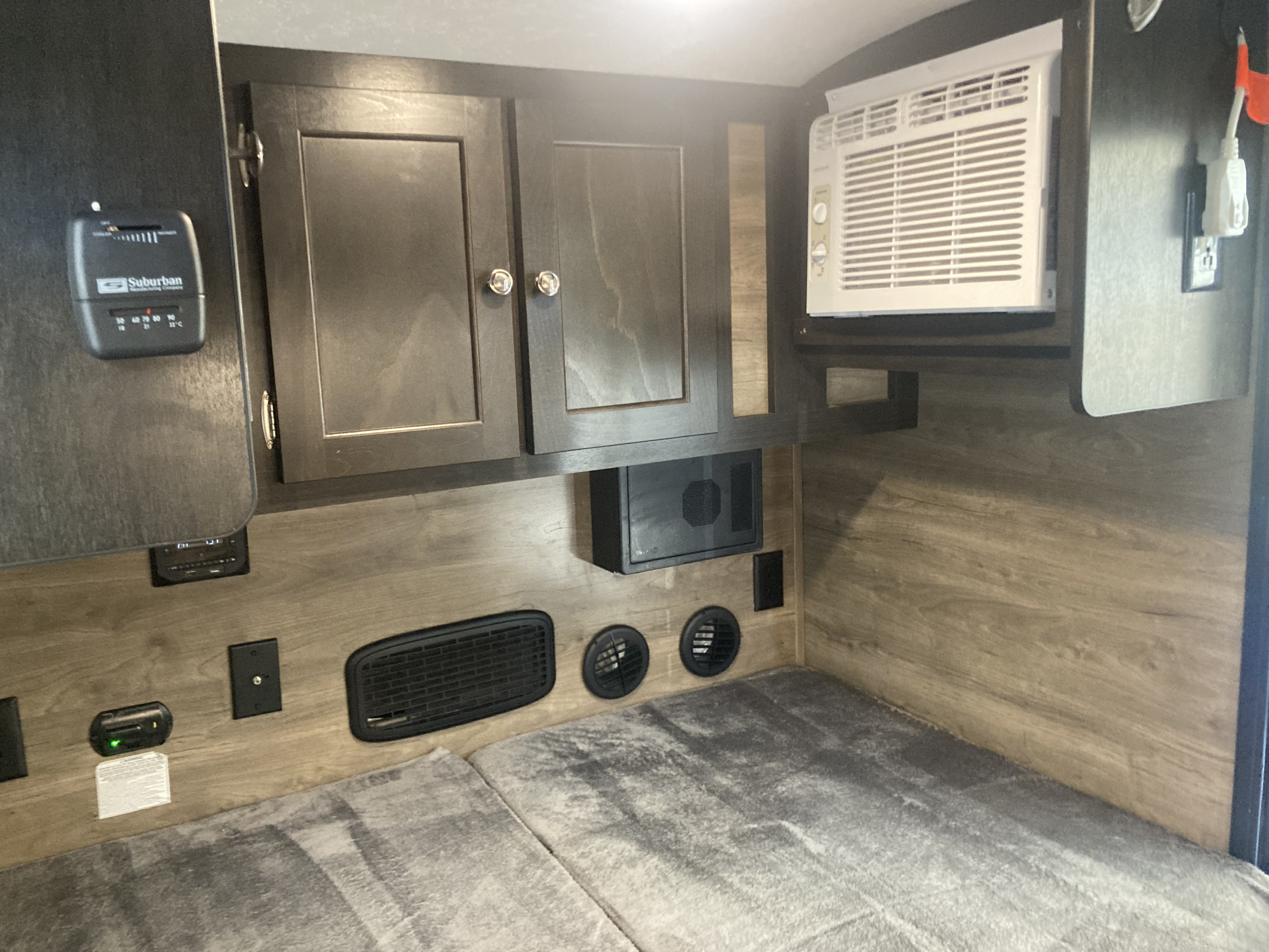 RV rental bedroom features a built-in AC unit, Suburban thermostat, overhead cabinets, and floor-level vents.. Braxton Creek Bushwhacker 2022