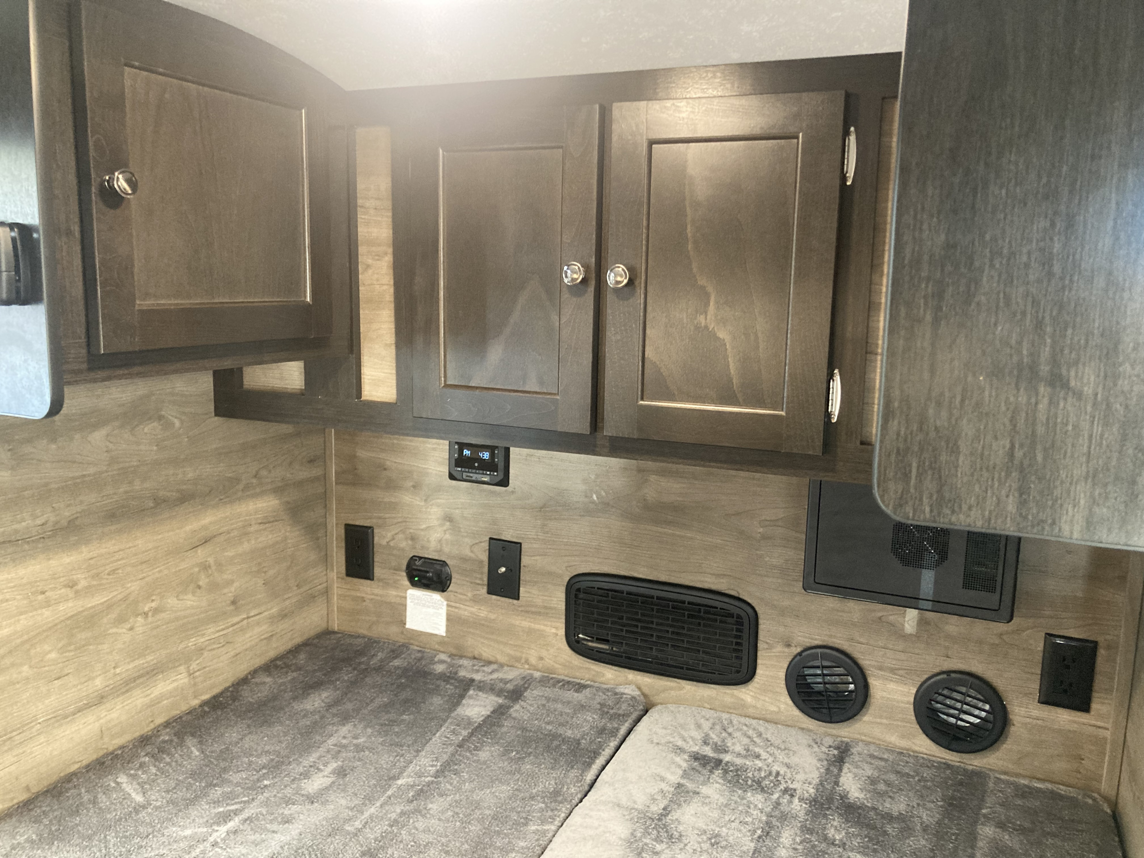 RV rental bunk with overhead cabinets, electrical outlets, and ventilation system.. Braxton Creek Bushwhacker 2022