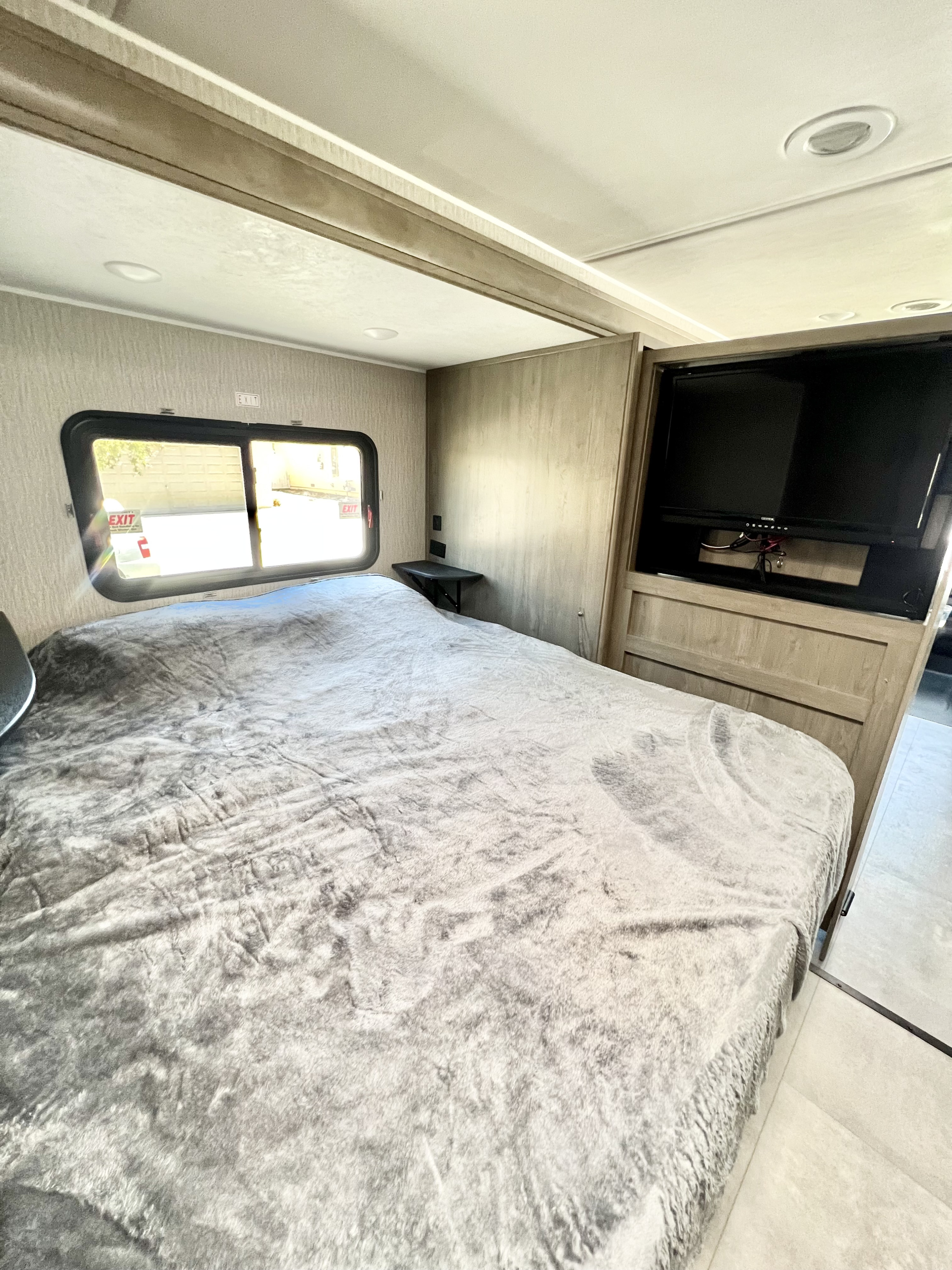 Cozy RV rental bedroom with large bed, grey blanket, window, and TV. Perfect for comfortable travels.. Coachmen Prism Elite 24FS 2023
