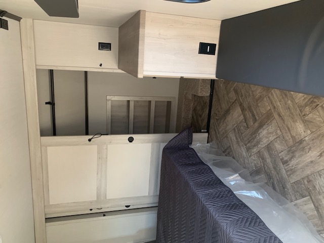RV rental interior: bedroom features a protected bed, herringbone flooring, and built-in overhead storage for your travels.. Forest River Wildcat 2023