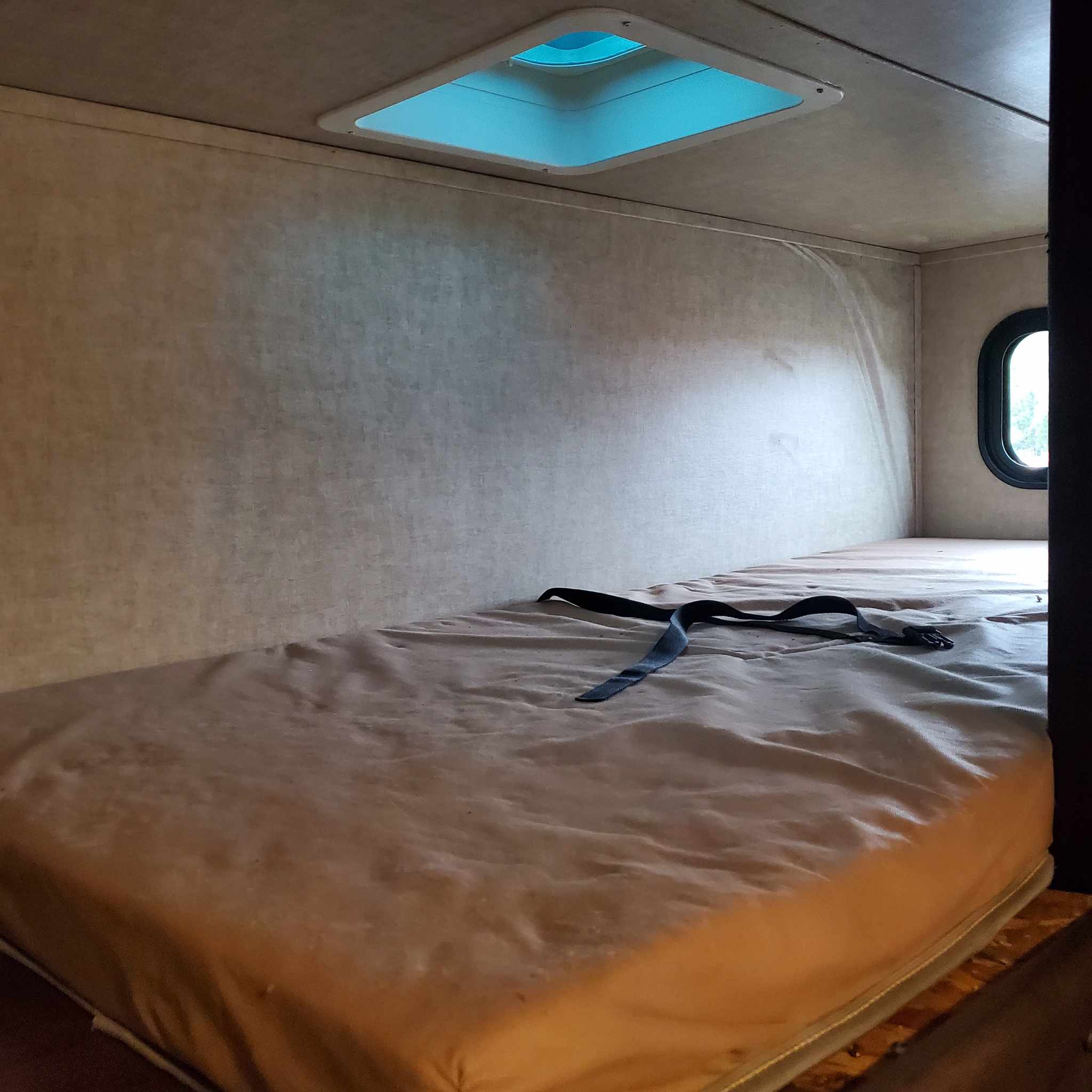 Cozy RV rental bunk bed interior with a bright skylight and a small window, perfect for compact living.. Keystone RV Fuzion Toy Hauler 2016