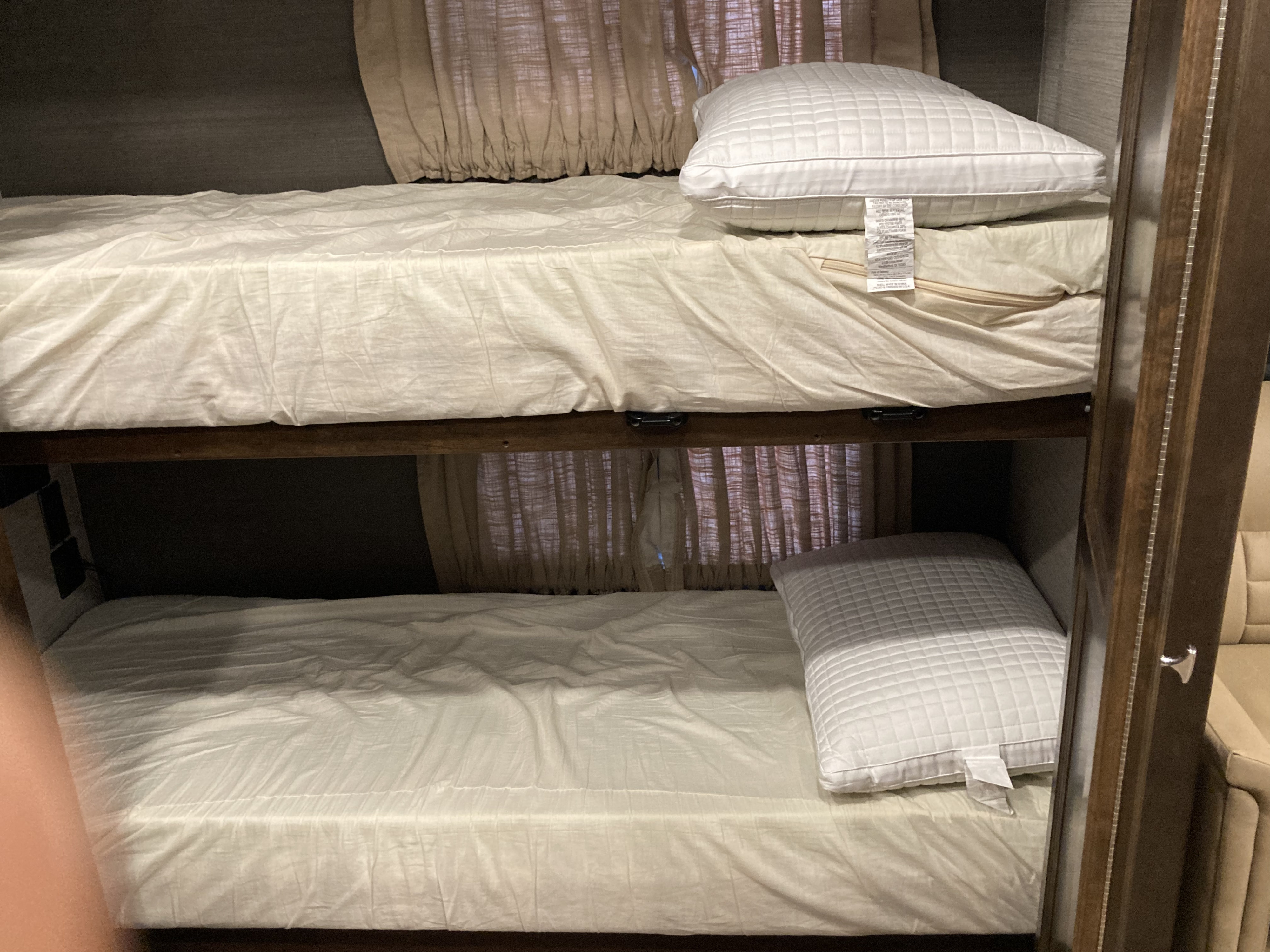 Comfortable upper and lower bunk beds with white bedding and pillows in an RV rental, perfect for family adventures.. Allegro Allegro Open Road 2019