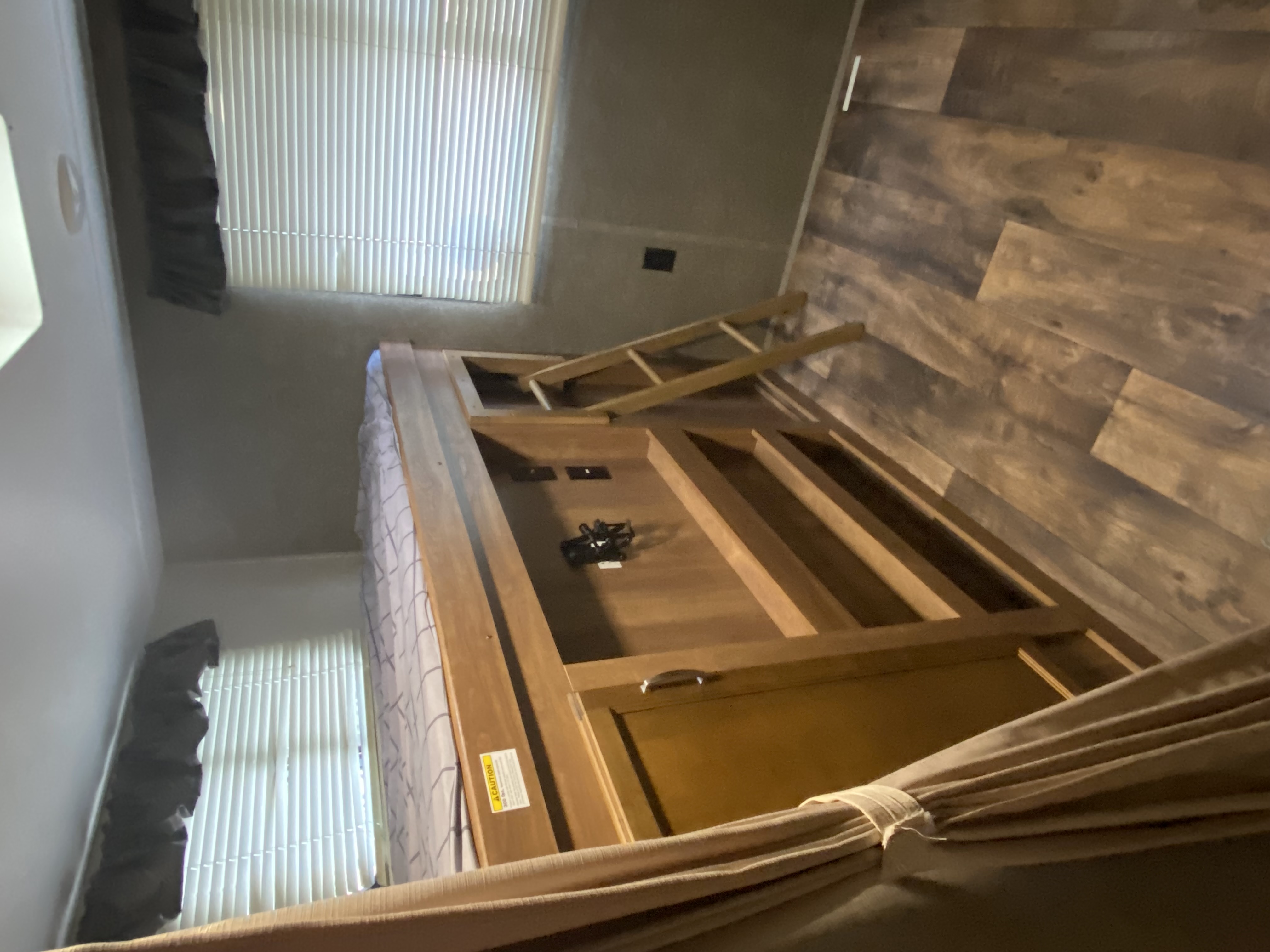 RV rental interior: Wooden bunk bed with ladder, patterned sheets, wood-look floor, and window blinds. Cozy and functional.. Keystone RV Springdale 2017