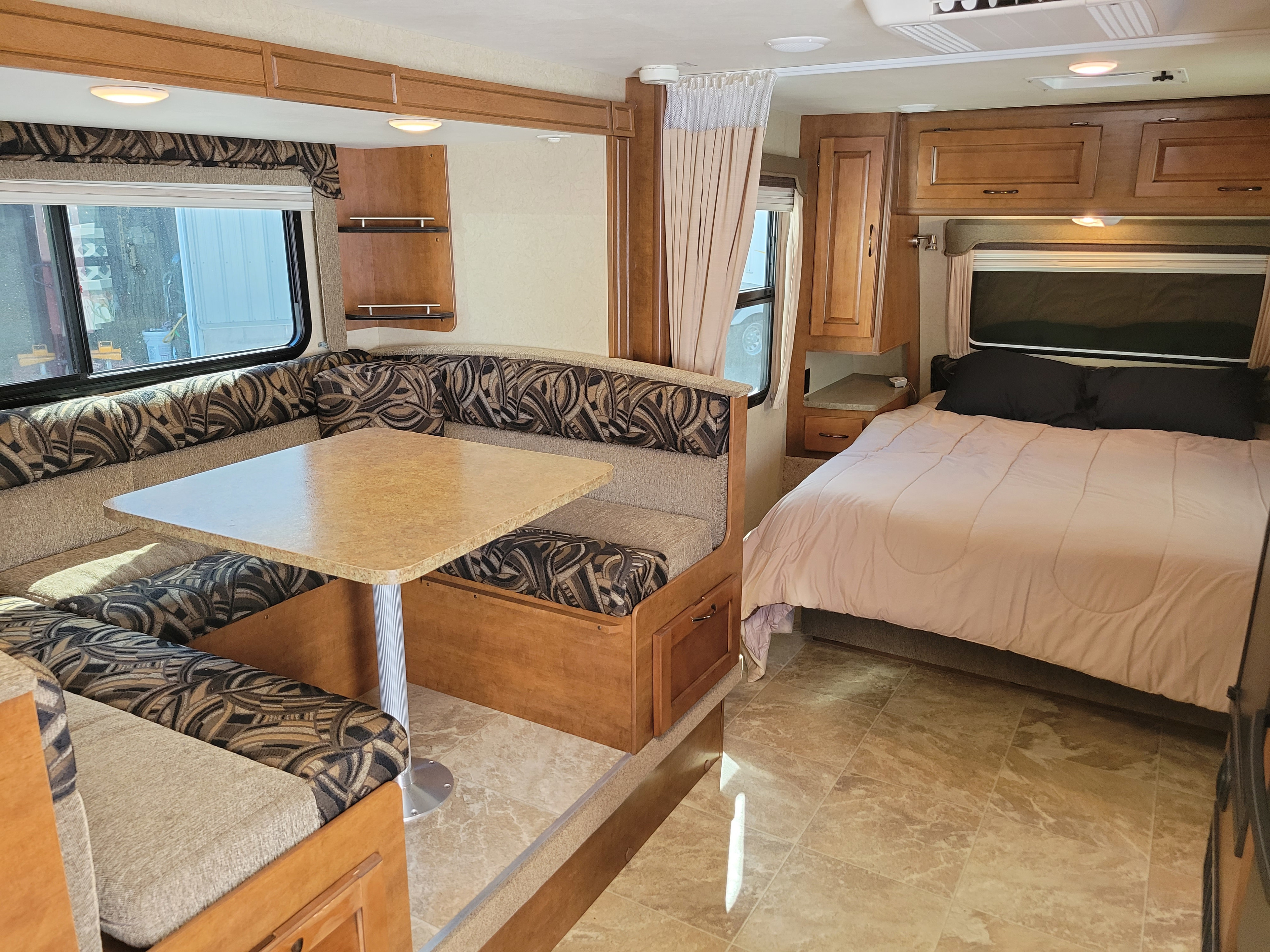 This RV rental offers a U-shaped dinette, dining table, and cozy bedroom with light bedding, perfect for travel comfort.. Lance 1995 2015