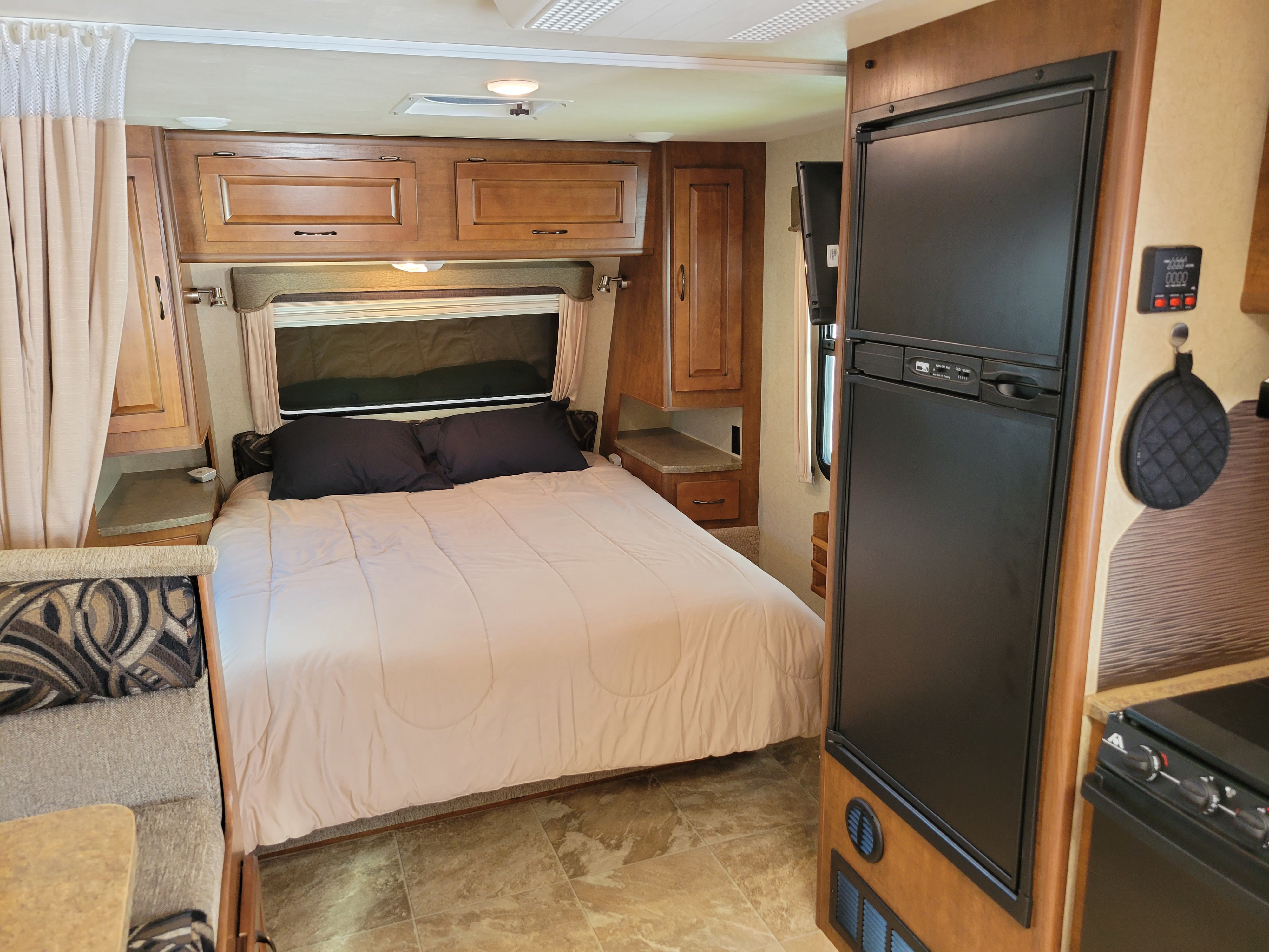 Relax in this RV rental's cozy bedroom with a queen bed, wood cabinetry, and convenient kitchen features for your travels.. Lance 1995 2015