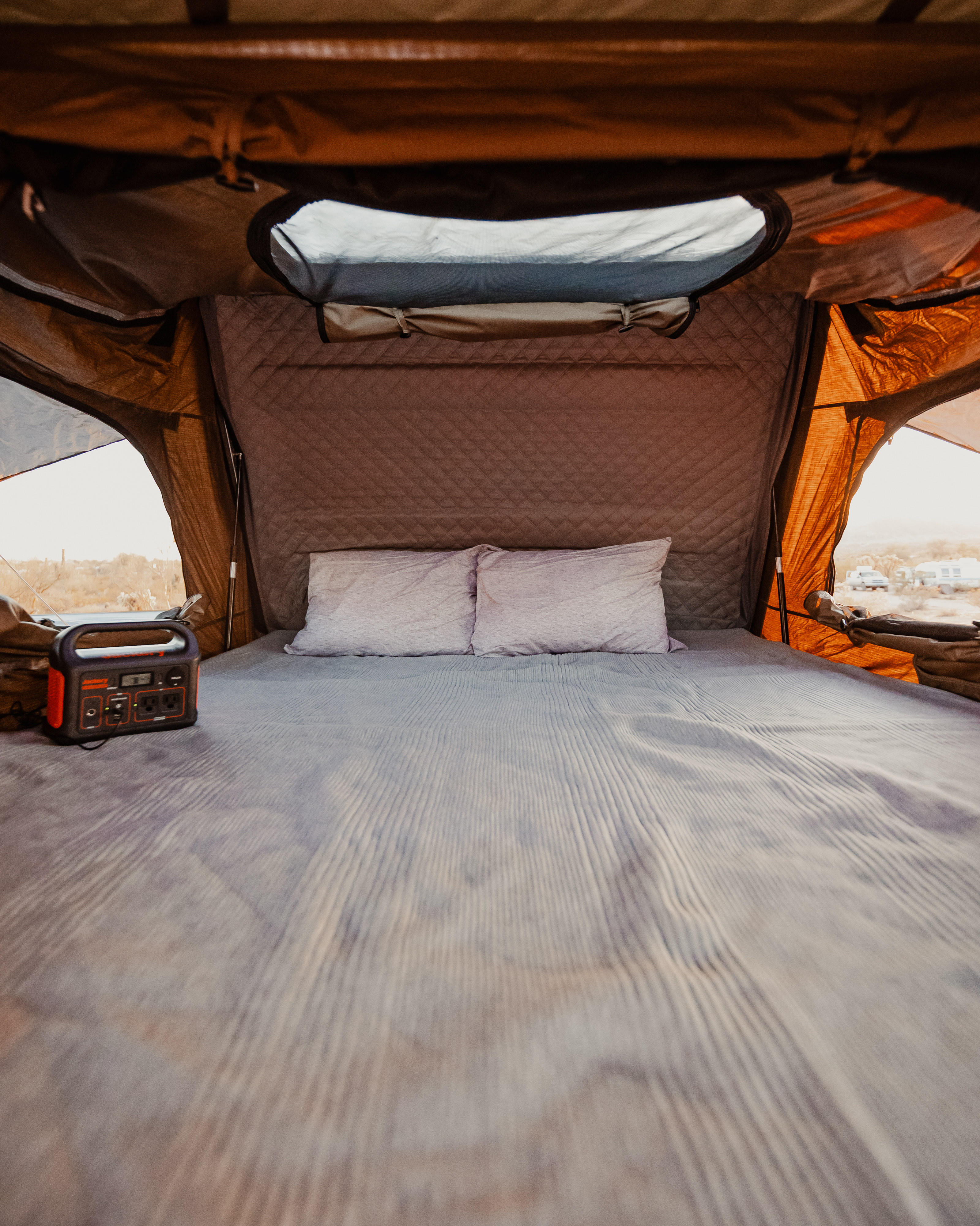 Cozy RV rental sleeping area with a comfortable bed and portable power station, offering desert views.. Jeep Wrangler 2022