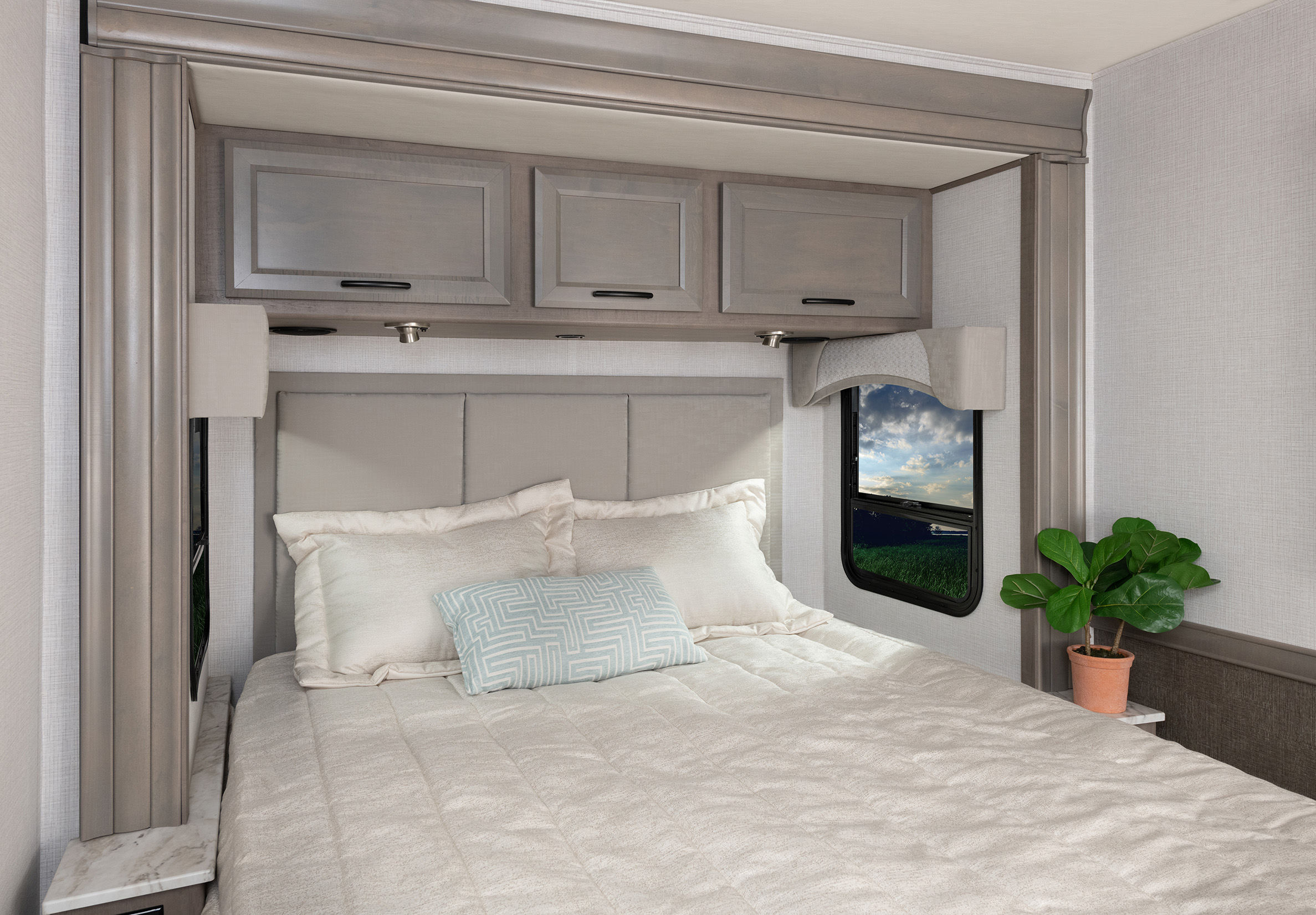 This RV rental's bedroom offers comfort with plush bedding, sleek overhead storage, and a picturesque window view.. Fleetwood Fortis 2024