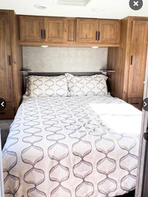 RV rental bedroom featuring a comfortable bed with patterned bedding, overhead storage cabinets, and side wardrobes.. Forester LE 2021
