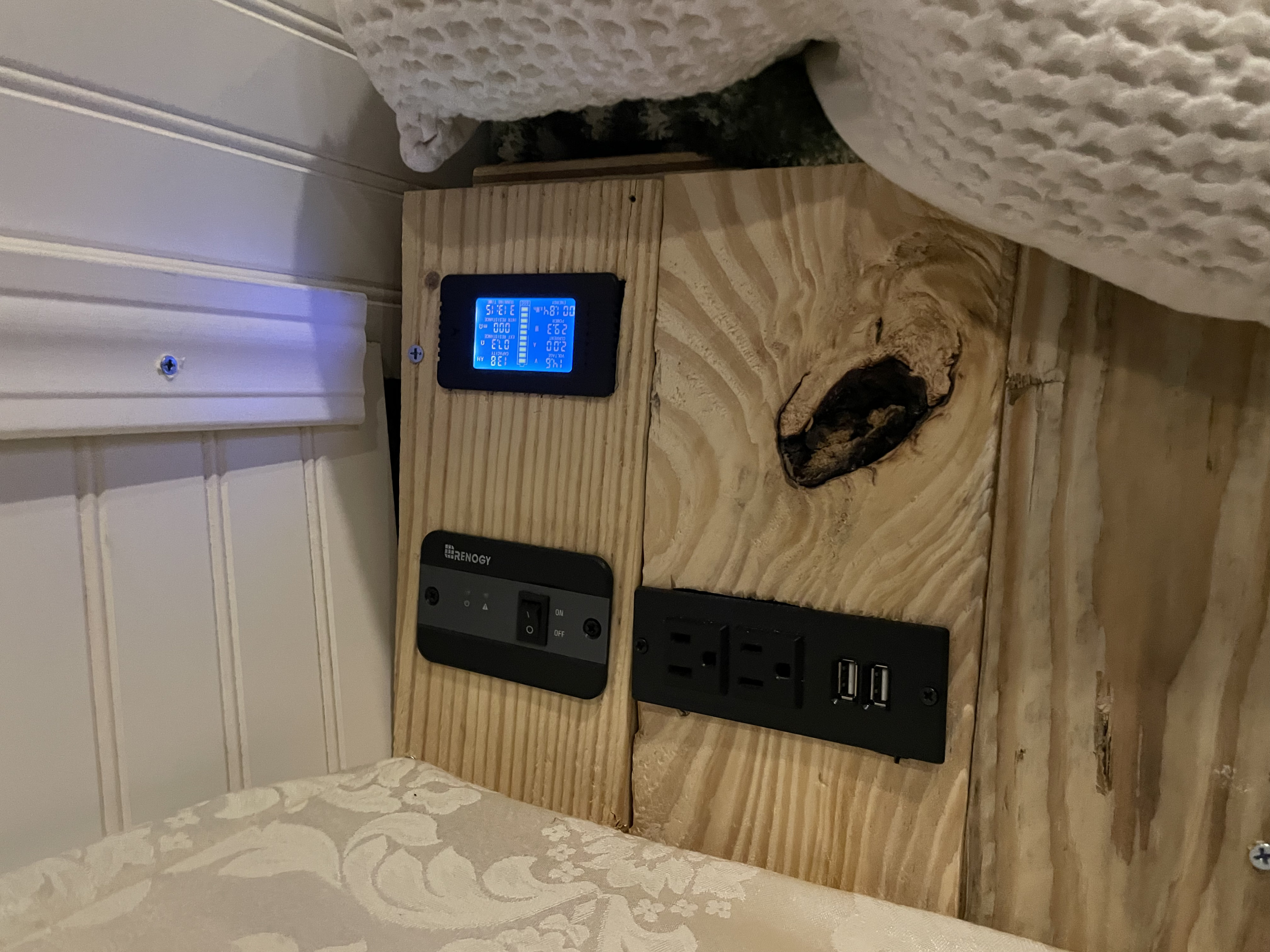 RV rental's power hub: Renogy battery monitor, inverter control, and AC/USB outlets on wood paneling.. Ford Econolline 250s 2007