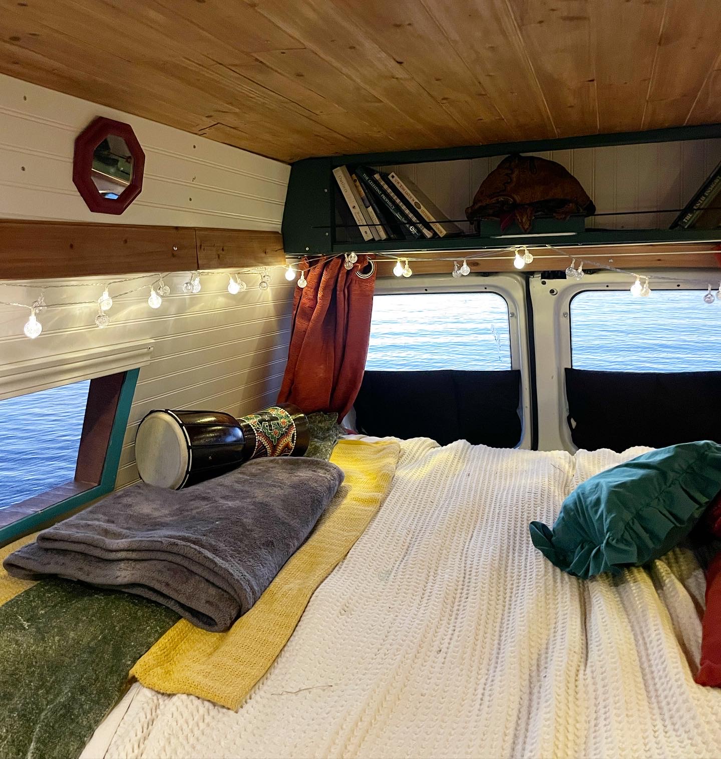 Cozy RV rental bedroom with string lights, a drum, and beautiful views of water from the open rear doors.. Ford Econolline 250s 2007