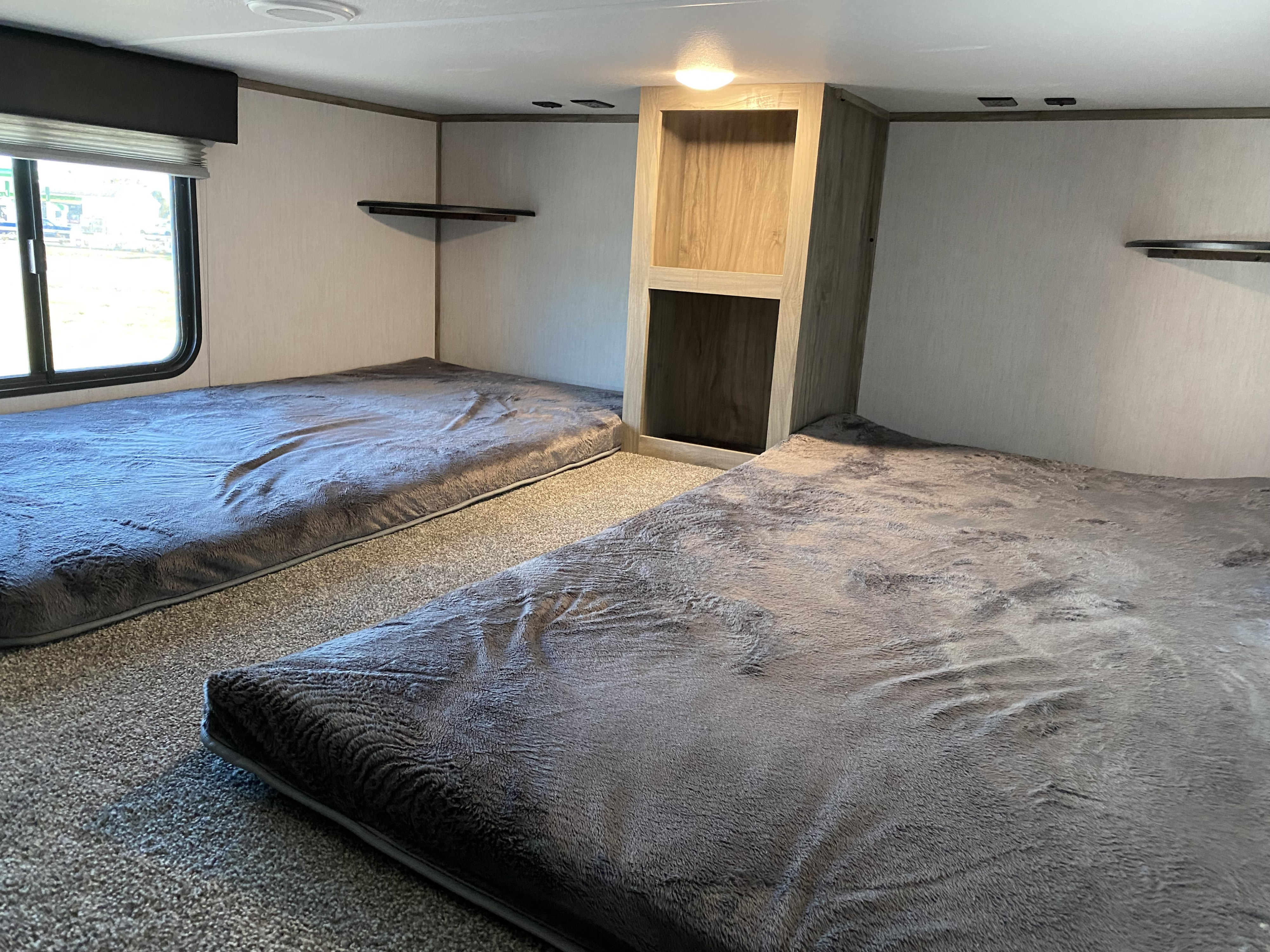 Cozy RV rental bunk room with two comfy beds, window, and built-in storage. Ideal for family adventures.. Forest River Cherokee Arctic Wolf 2022