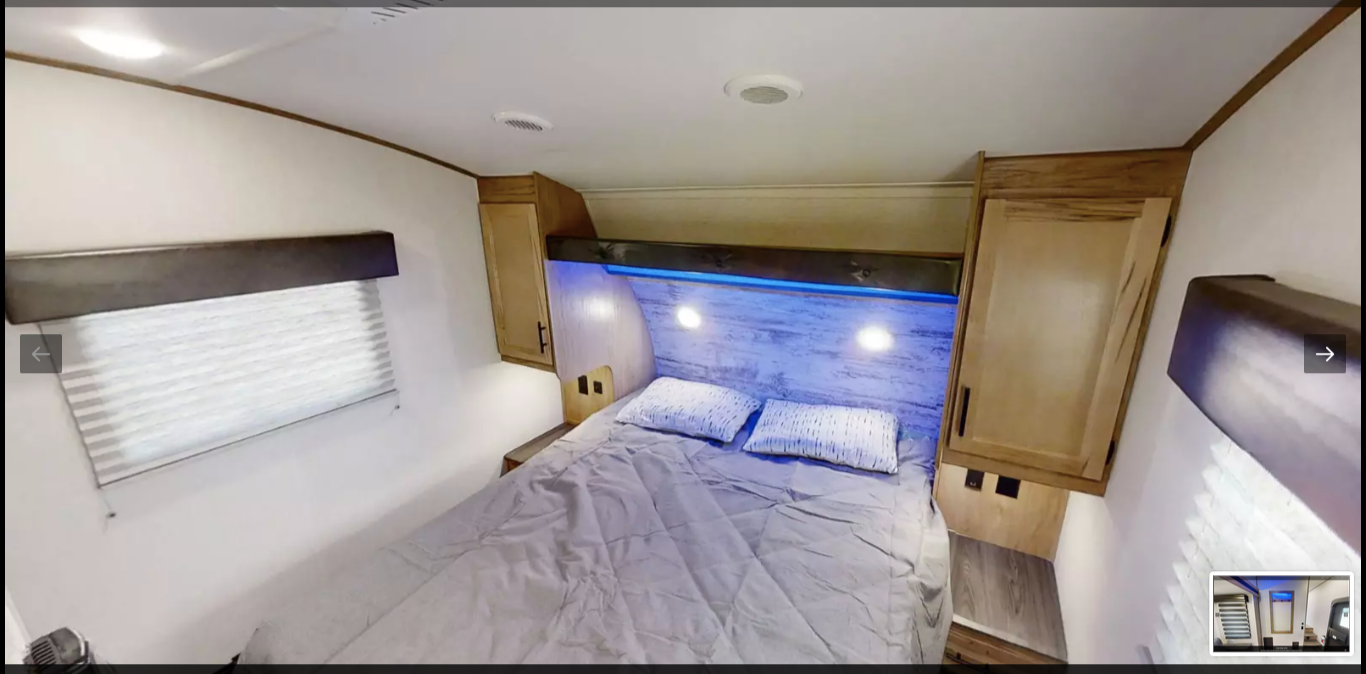 Cozy RV rental bedroom with a comfy bed, modern headboard lighting, and built-in storage. Ideal for your next adventure.. Forest River Cherokee Arctic Wolf 2021