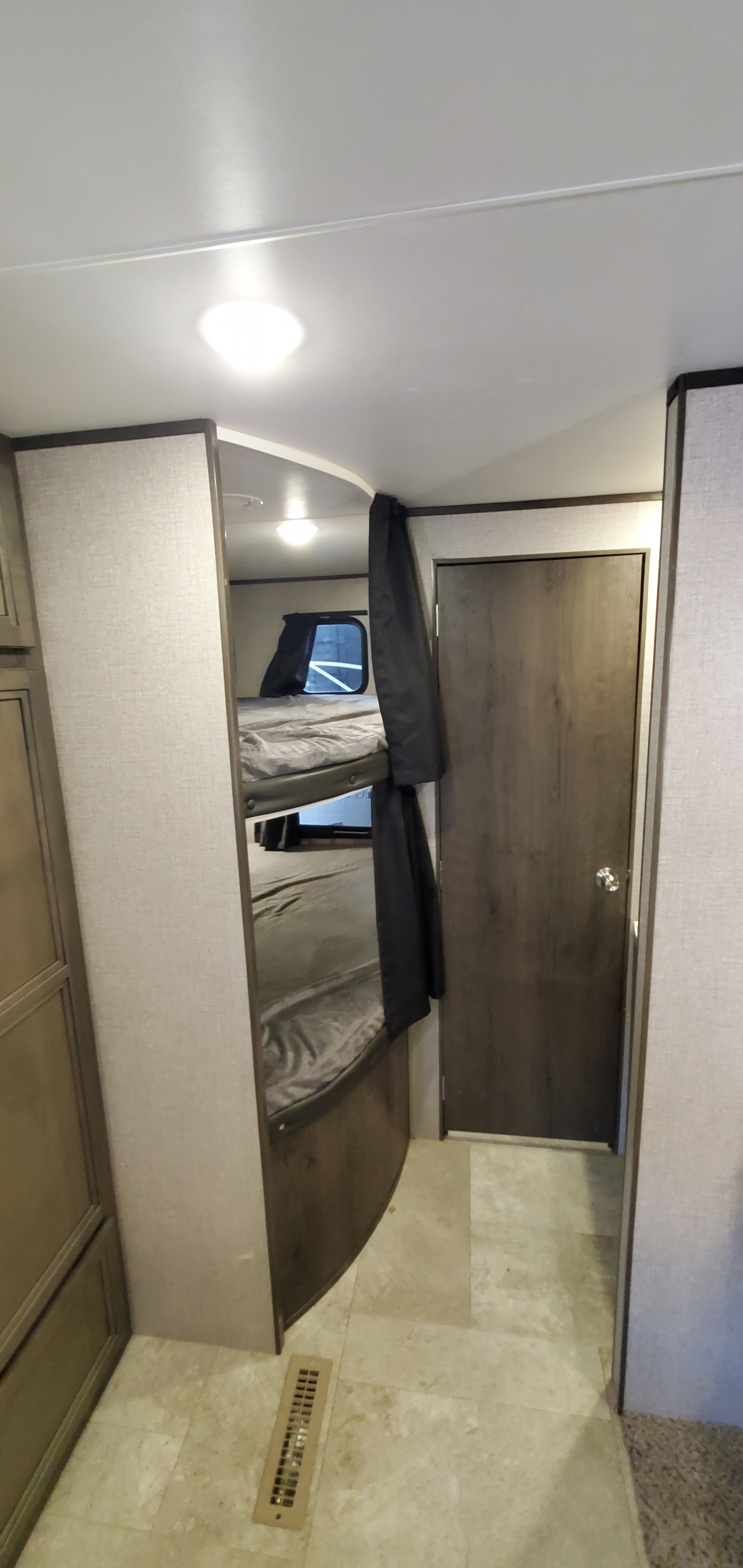 Cozy RV rental interior: bunk beds with privacy curtains, an adjacent door, and a floor vent are visible in this practical space.. Jayco Jay Flight SLX 2020