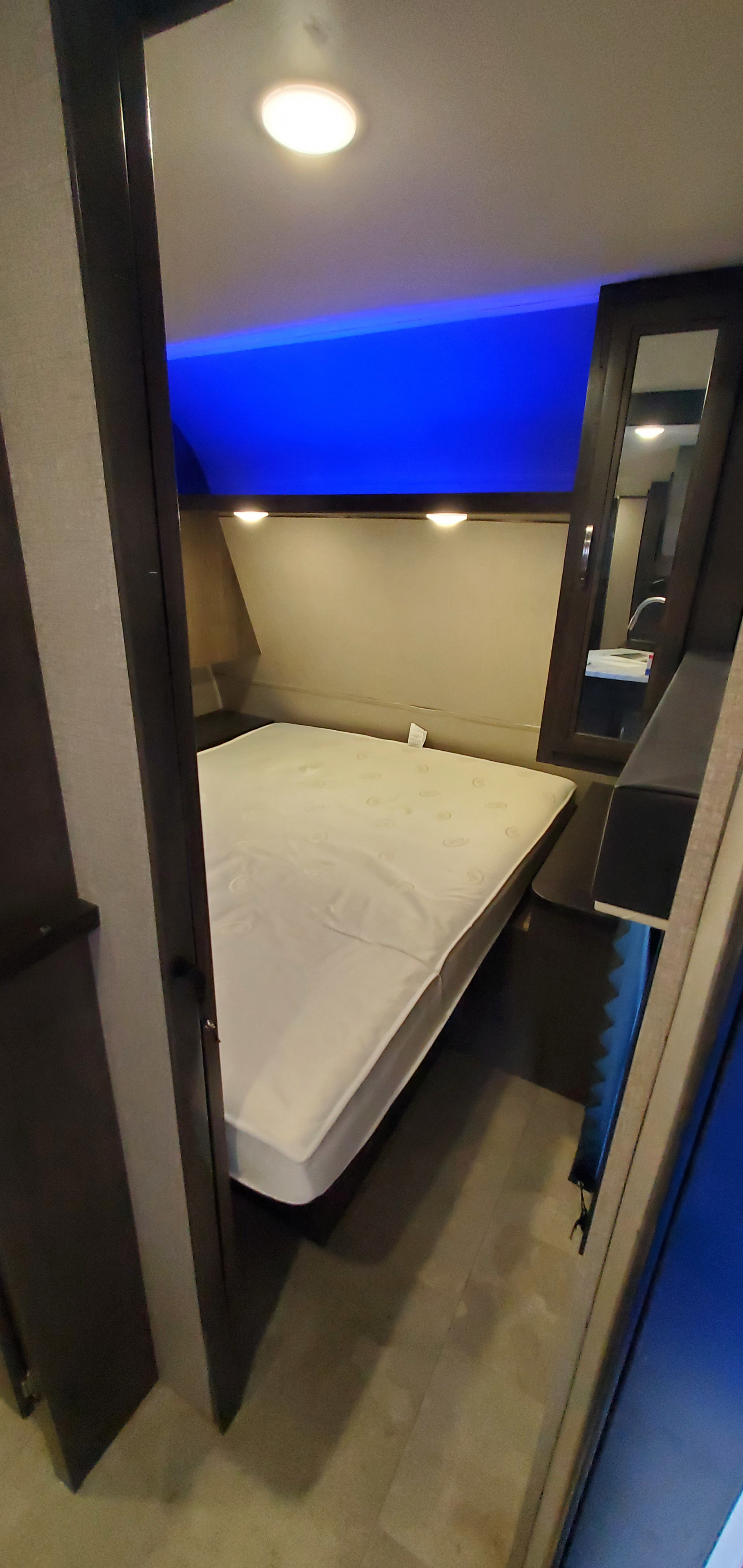 Explore this RV rental bedroom: a comfy mattress, striking blue overhead light, and a mirrored cabinet reflecting a sink.. Jayco Jay Flight SLX 2020