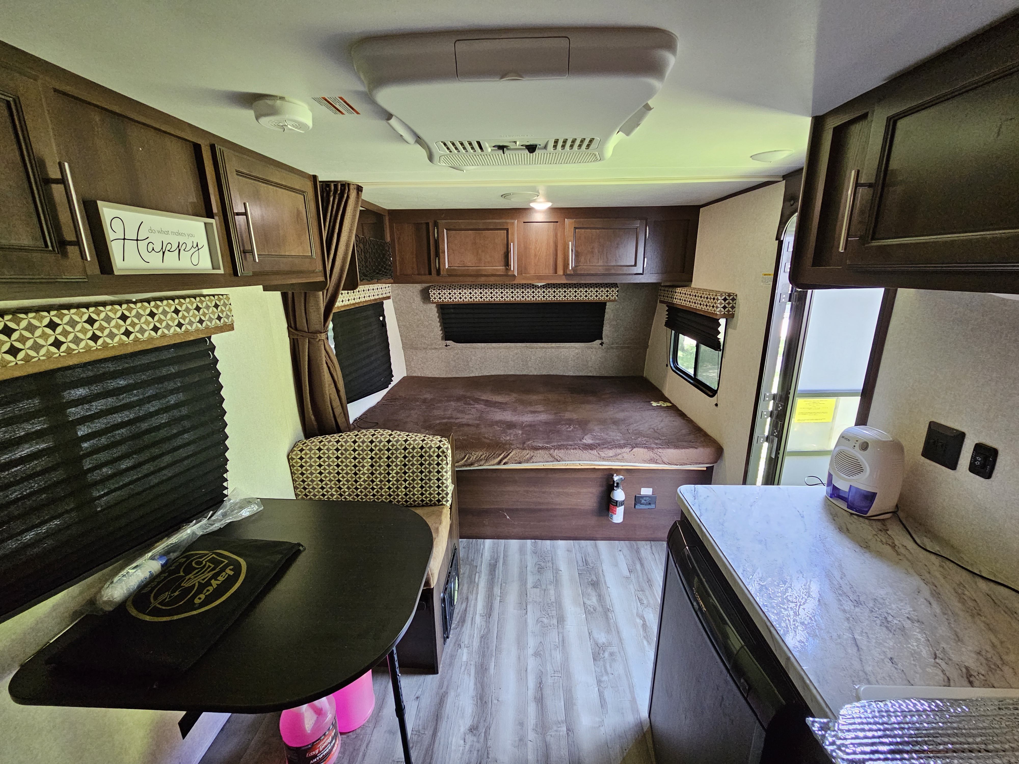 Cozy rv rental interior featuring a bed, dinette table, and compact kitchen, ideal for comfortable travel.. Jayco Jay Flight SLX 2019