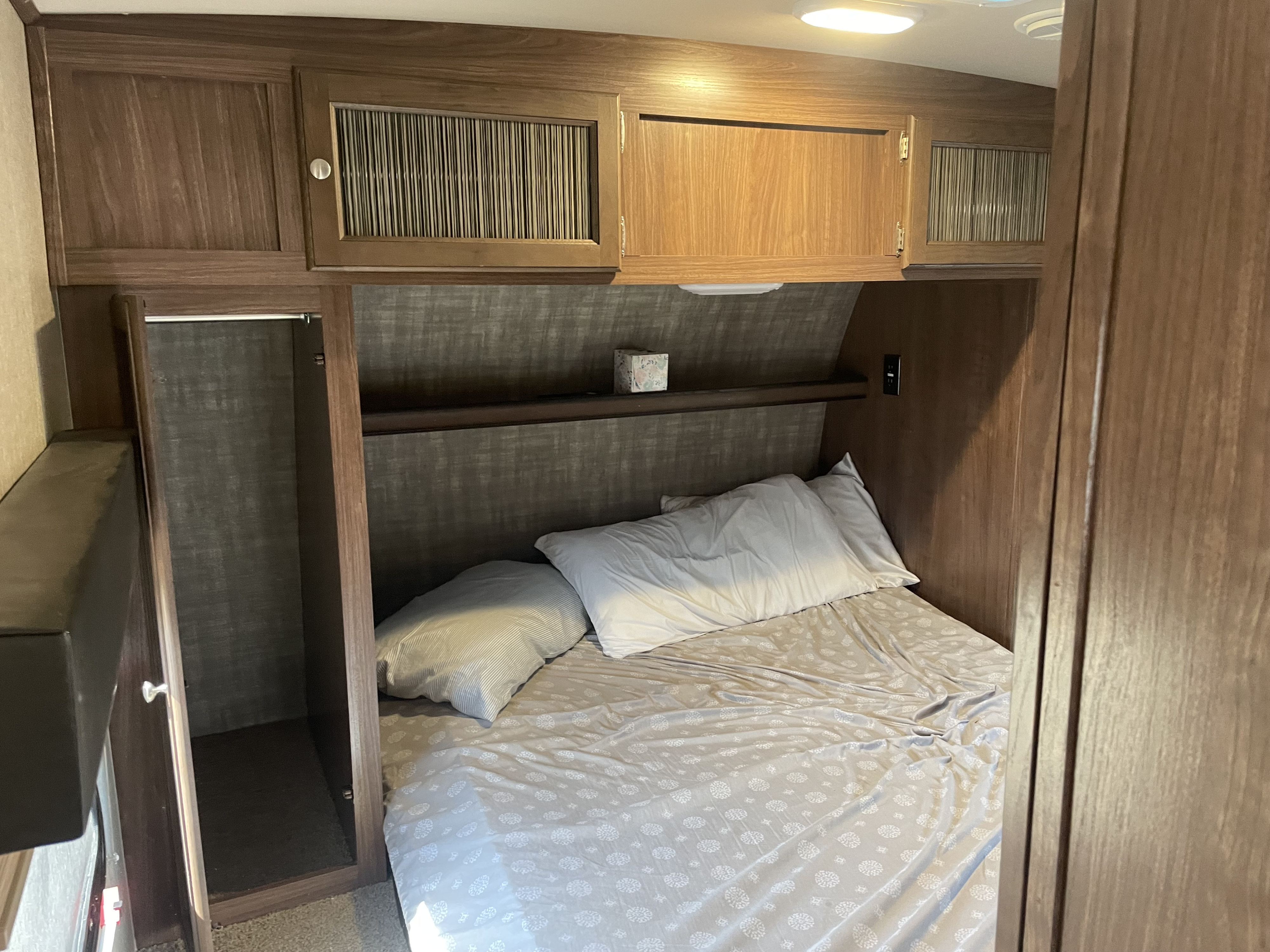 Spacious RV rental bedroom featuring a cozy bed, ample overhead storage, and a convenient built-in closet.. Forest River Palomino Solaire 2015