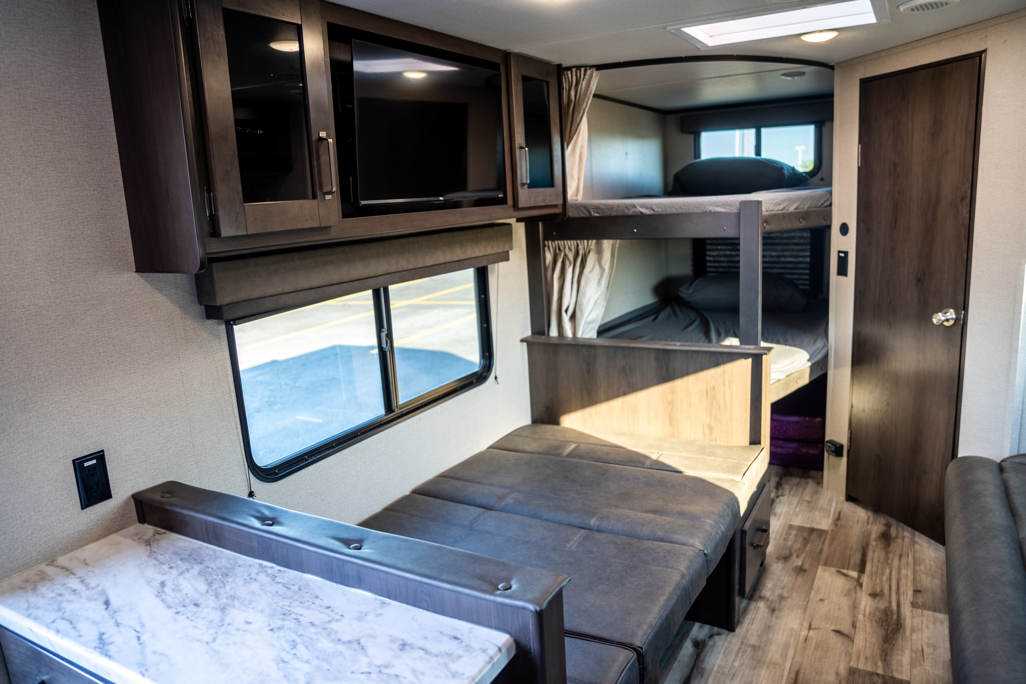 Spacious RV rental interior with dinette, kitchen, TV, and bunk beds. Perfect for family adventures.. Grand Design Transcend Xplor 2023