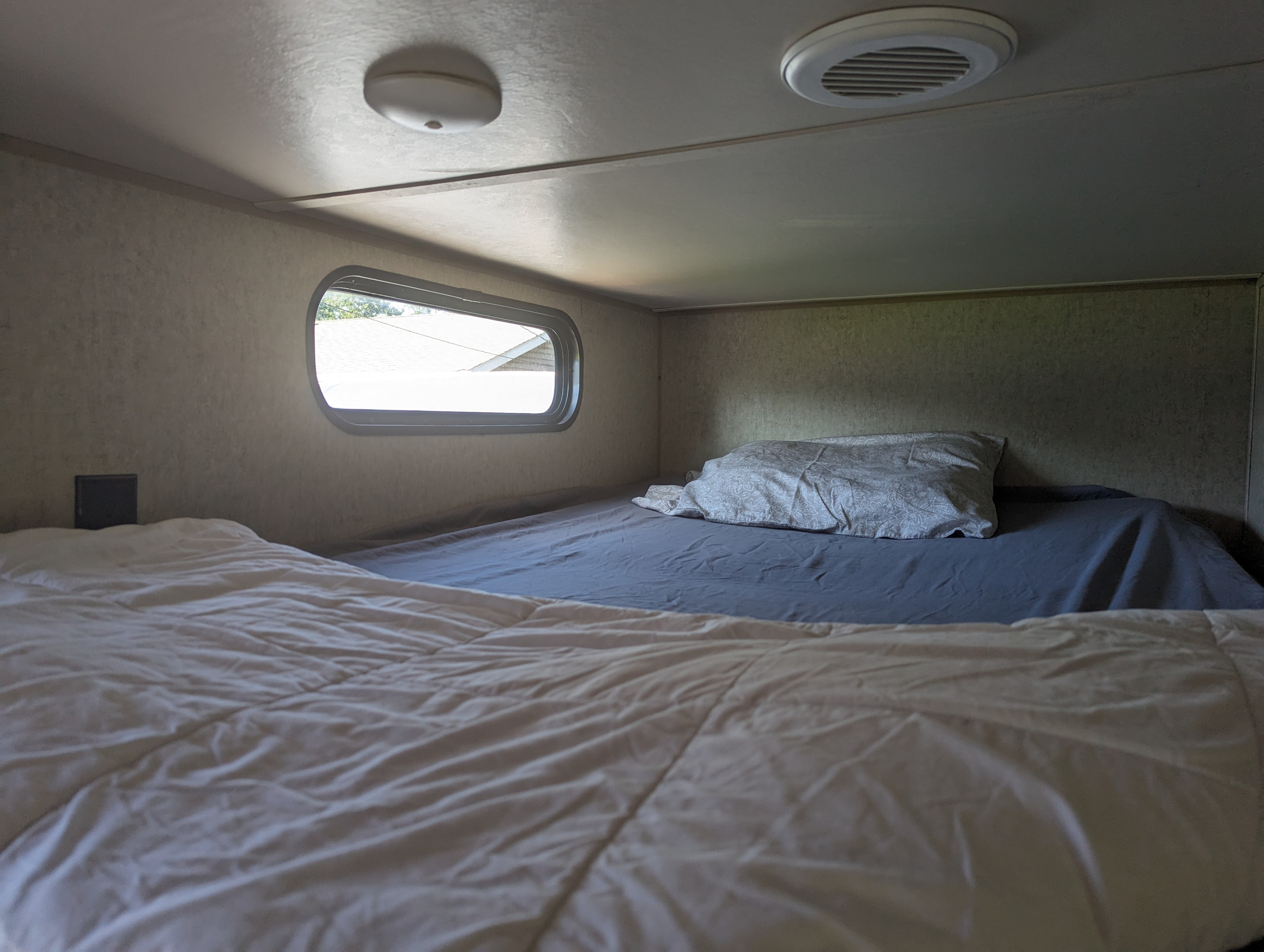 Cozy RV rental interior with bunk beds, a window view, ceiling light, and vent for comfortable lodging.. Forest River Cherokee 2016